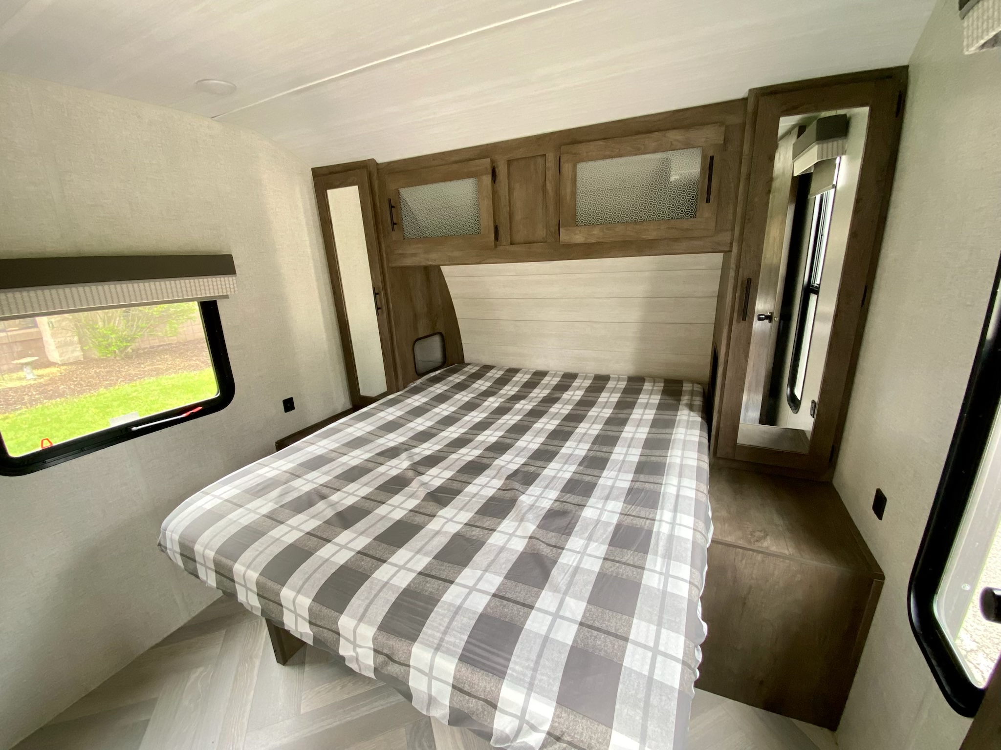 RV rental bedroom showcasing a plaid bed, modern wood cabinets, and a window providing natural light.. wildwood 32BHDS 2021