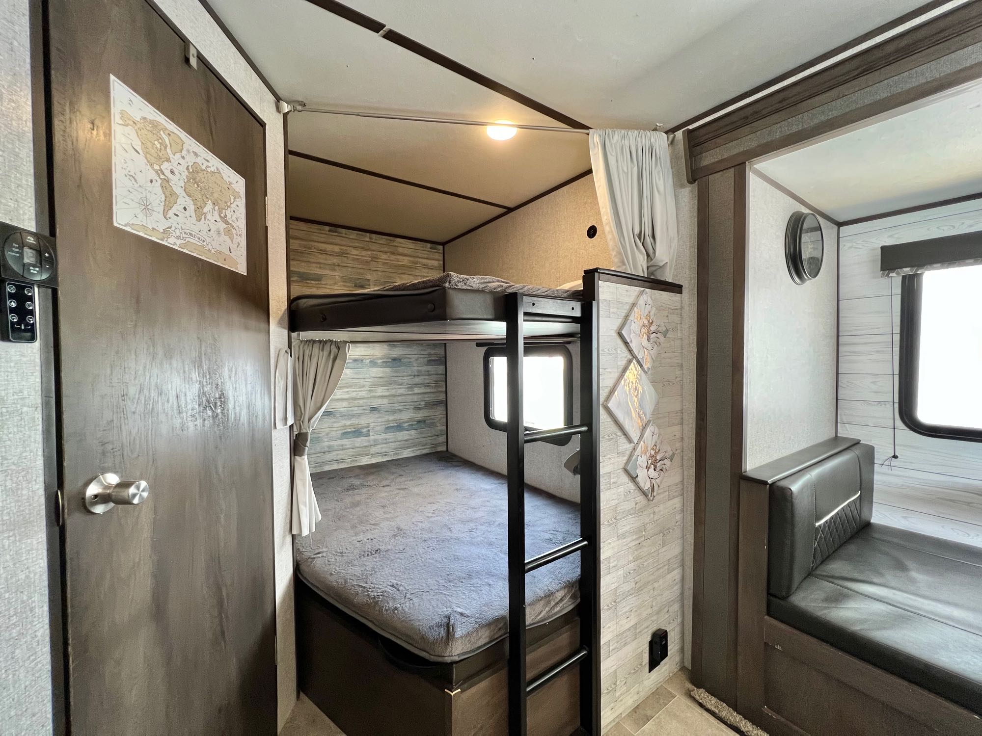Inside an RV rental: cozy bunk beds, a handy ladder, and a comfortable bench seat for your adventures. World map decor adds charm.. Dutchmen Coleman 2021