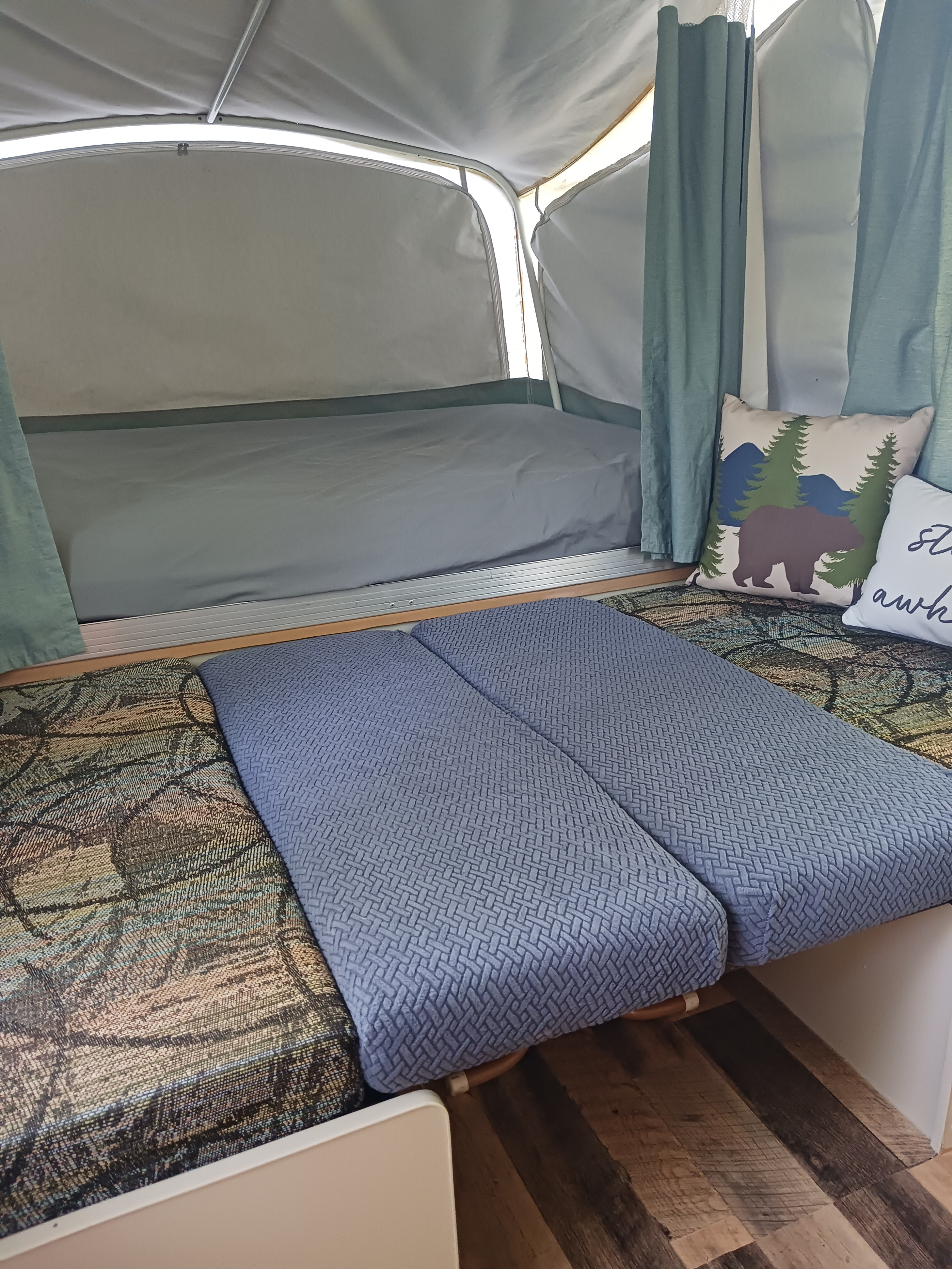 RV rental interior: a comfy bed, blue cushions, and a bear pillow in a cozy pop-up camper.. Coleman Other 2002