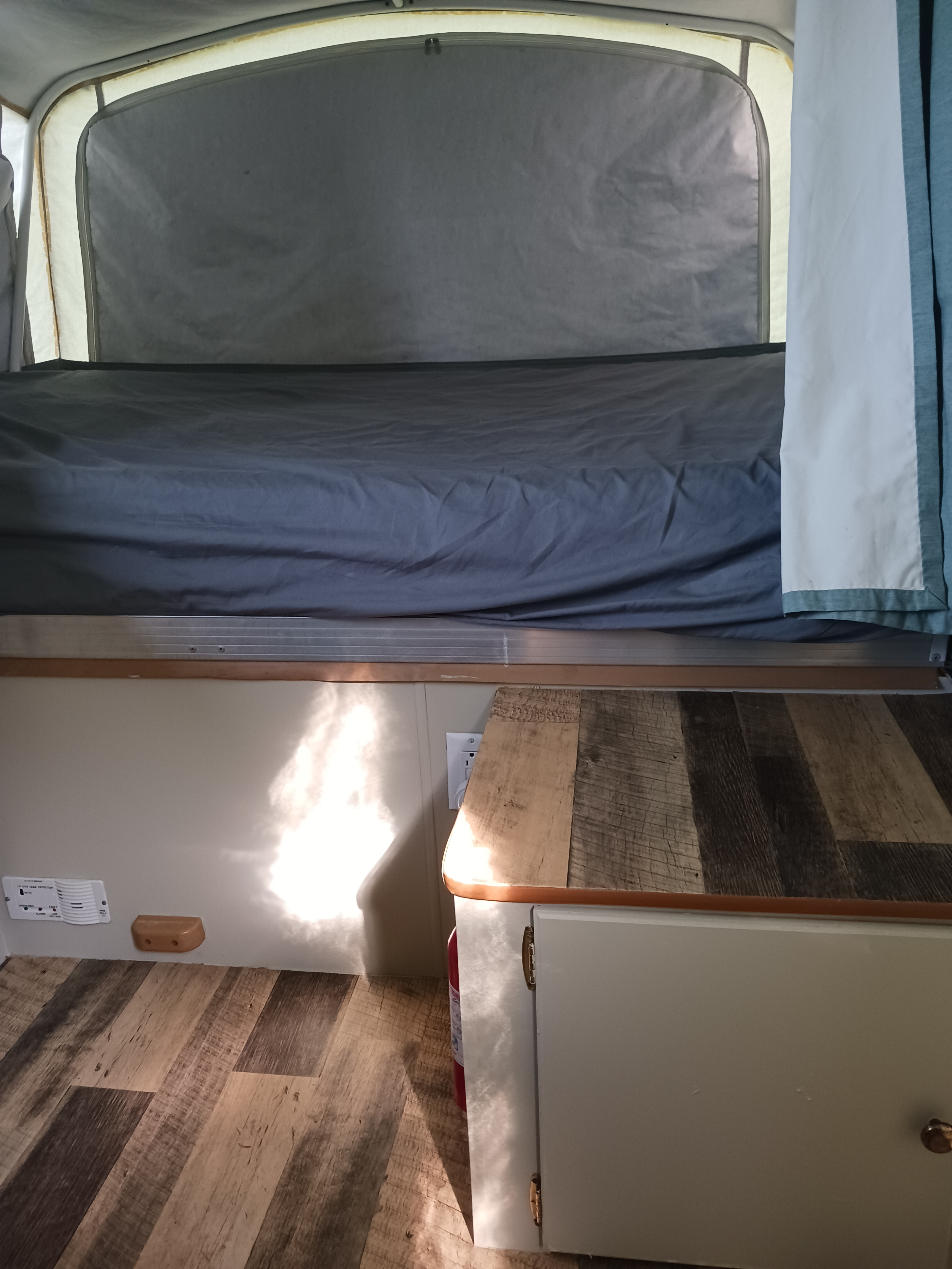 Cozy RV rental interior with bed, wood counter, and safety features like an LP gas detector and fire extinguisher.. Coleman Other 2002