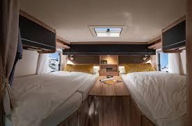 Inside an RV rental: a comfy motorhome bedroom featuring twin beds separated by an aisle, with overhead storage & skylight.. Hymer MLT 570 Crossover 2023