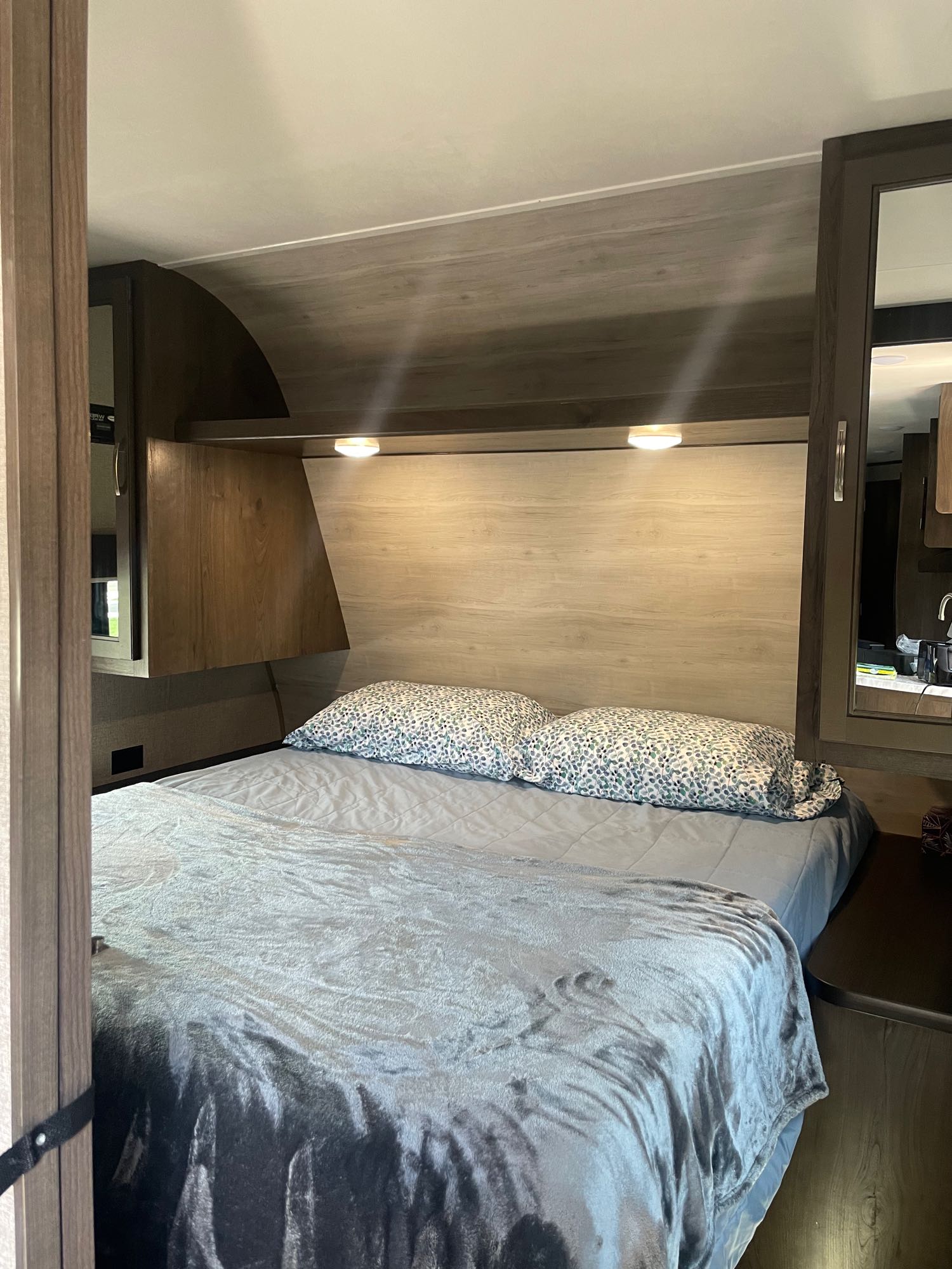 Inside a compact RV rental bedroom, featuring a neatly made bed with soft linens and overhead lighting.. Jayco Jay Flight SLX 2021
