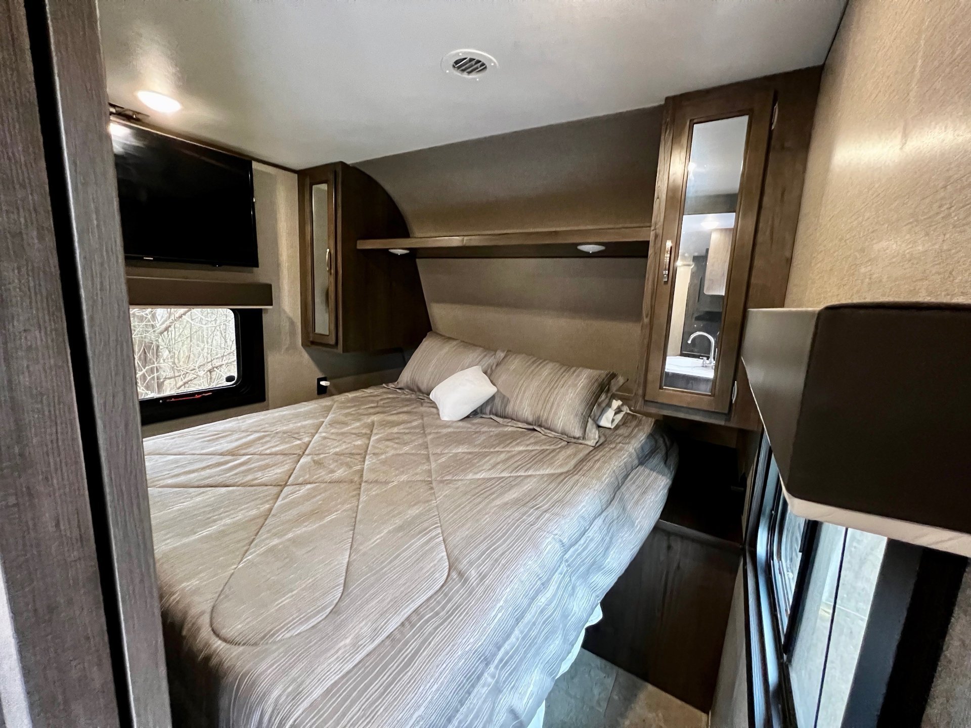 Cozy RV rental bedroom featuring a spacious bed, wall-mounted TV, and convenient overhead storage for a comfortable stay.. Jayco Jay Flight SLX 2020
