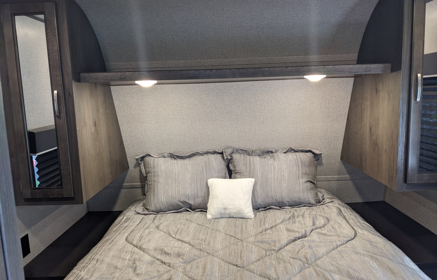 Cozy grey bedroom in an RV rental, featuring a comfortable bed, overhead lighting, and compact storage.. Jayco Jay Flight SLX 2020