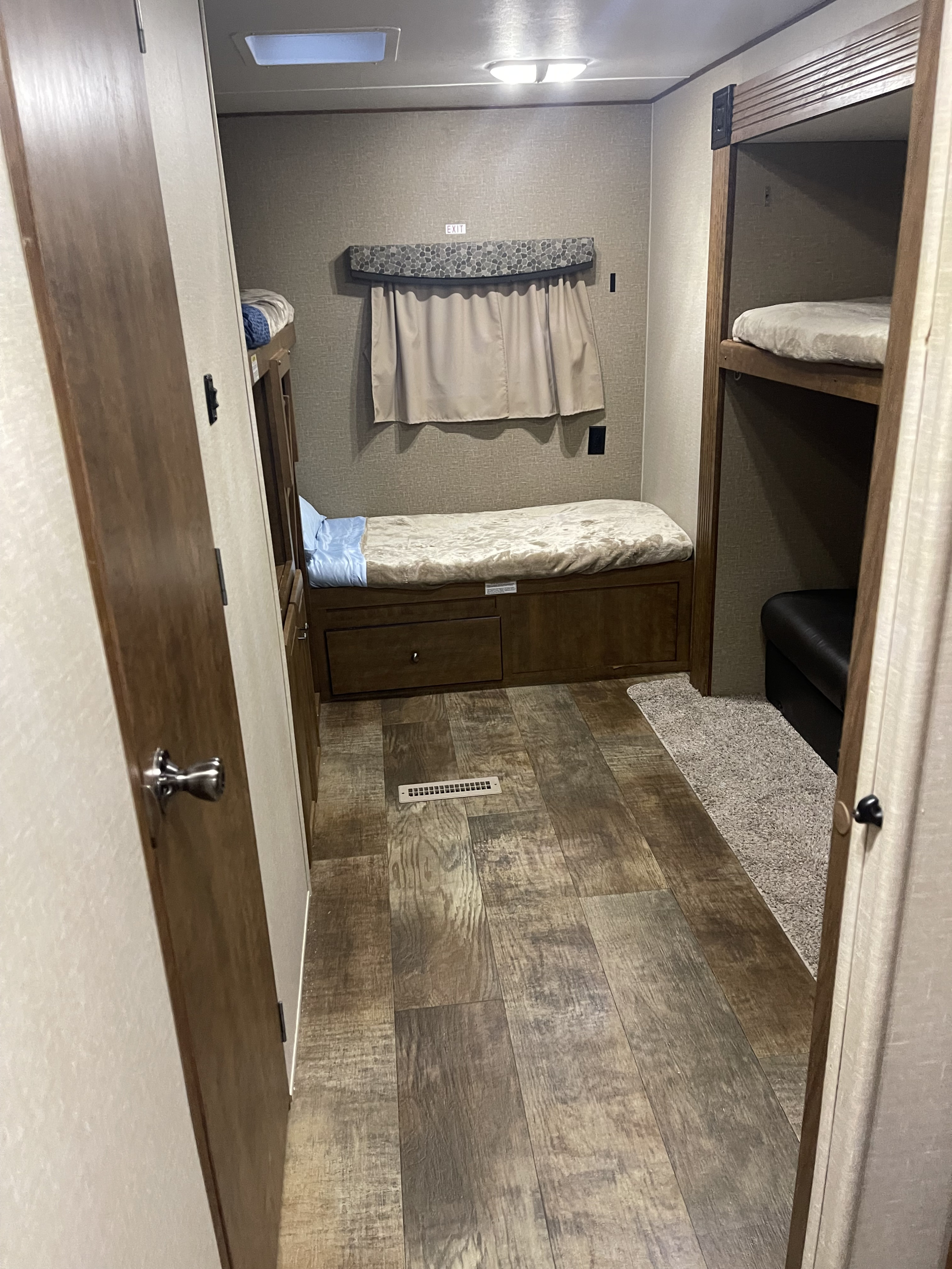 RV rental interior: hallway leading to cozy sleeping areas with bunk beds, a lower bed with storage, and wood-look flooring.. Crossroads RV Z-1 2016