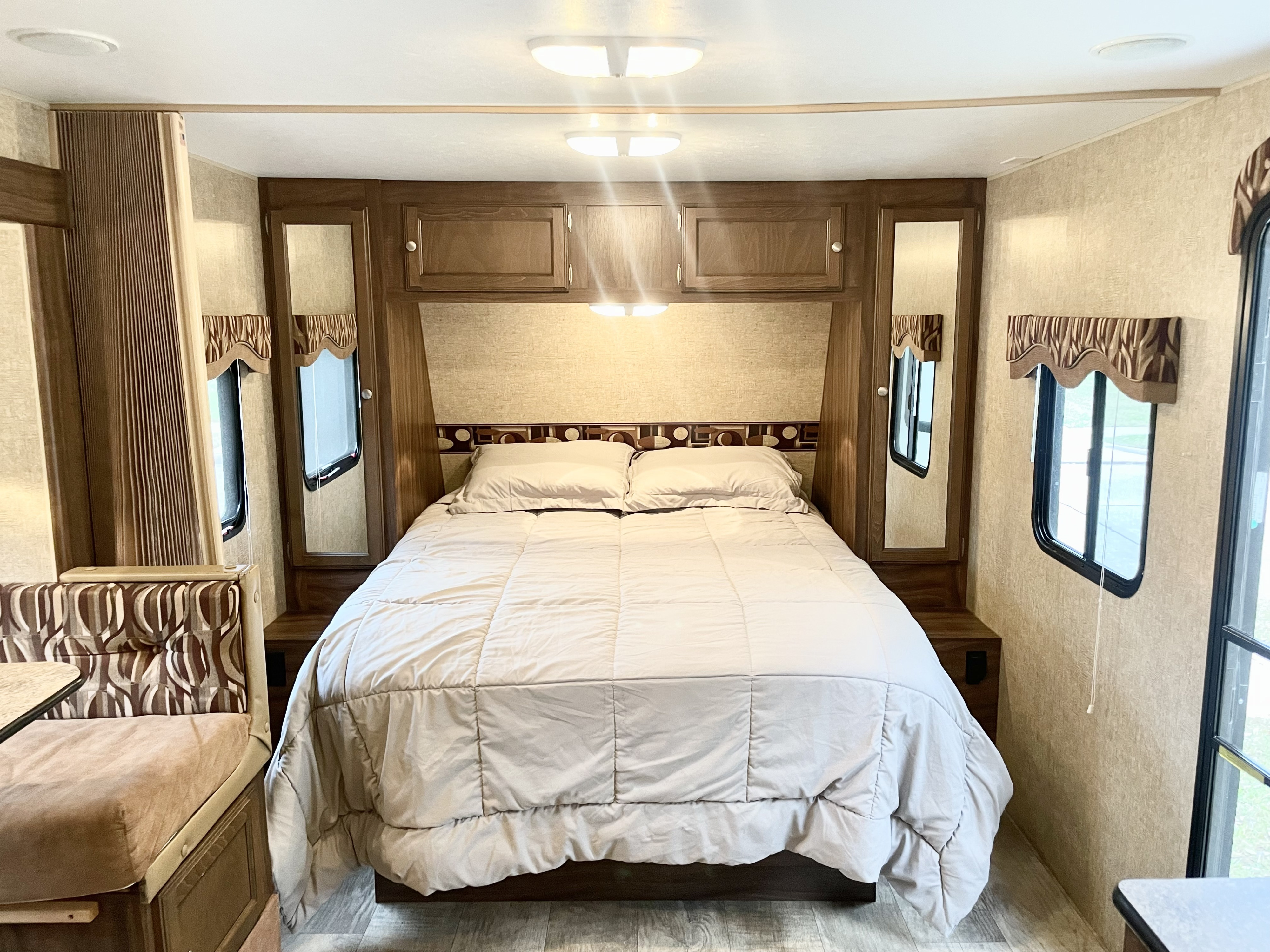 Cozy RV rental bedroom featuring a large bed, built-in cabinets, and dual windows. Perfect for comfortable travel.. Sportsmen Show Stopper 2016