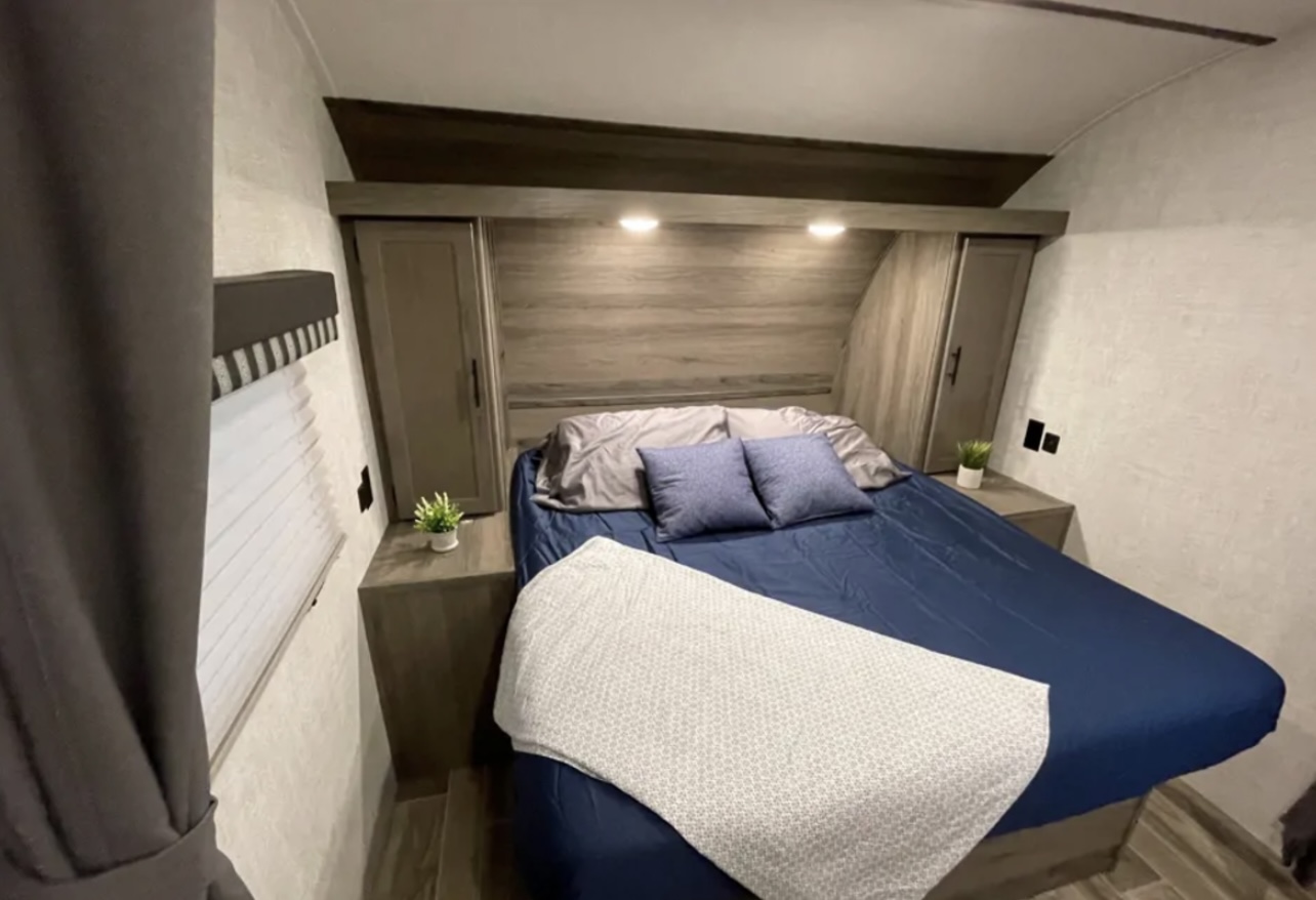 Cozy RV rental bedroom with a comfortable bed, overhead storage, and integrated lighting. Perfect for your next road trip!. Grandriver 25BH 2021