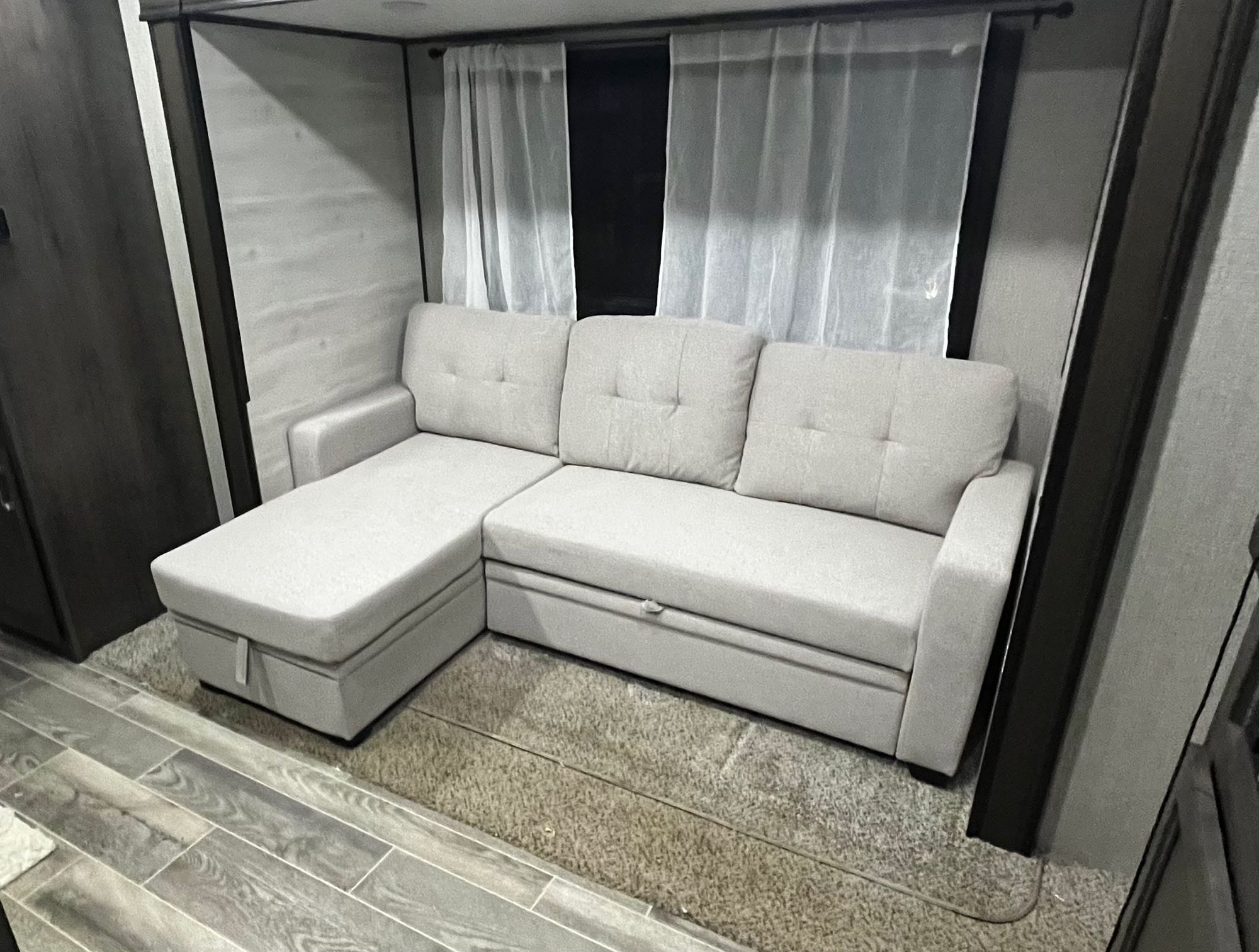 RV rental: light gray L-shaped sectional sofa with storage in a modern living area, sheer curtains.. Jayco Jay Flight SLX 2021