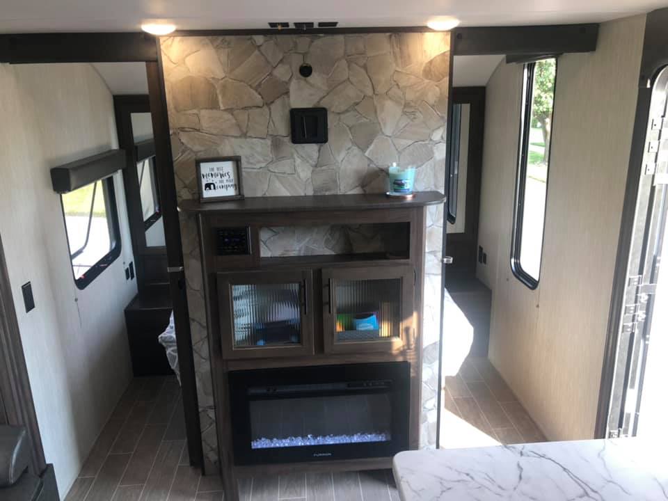 RV rental: Modern interior with a stone-look fireplace, entertainment unit, and wood-style flooring in a cozy living space.. Forest River Cherokee Grey Wolf 2021
