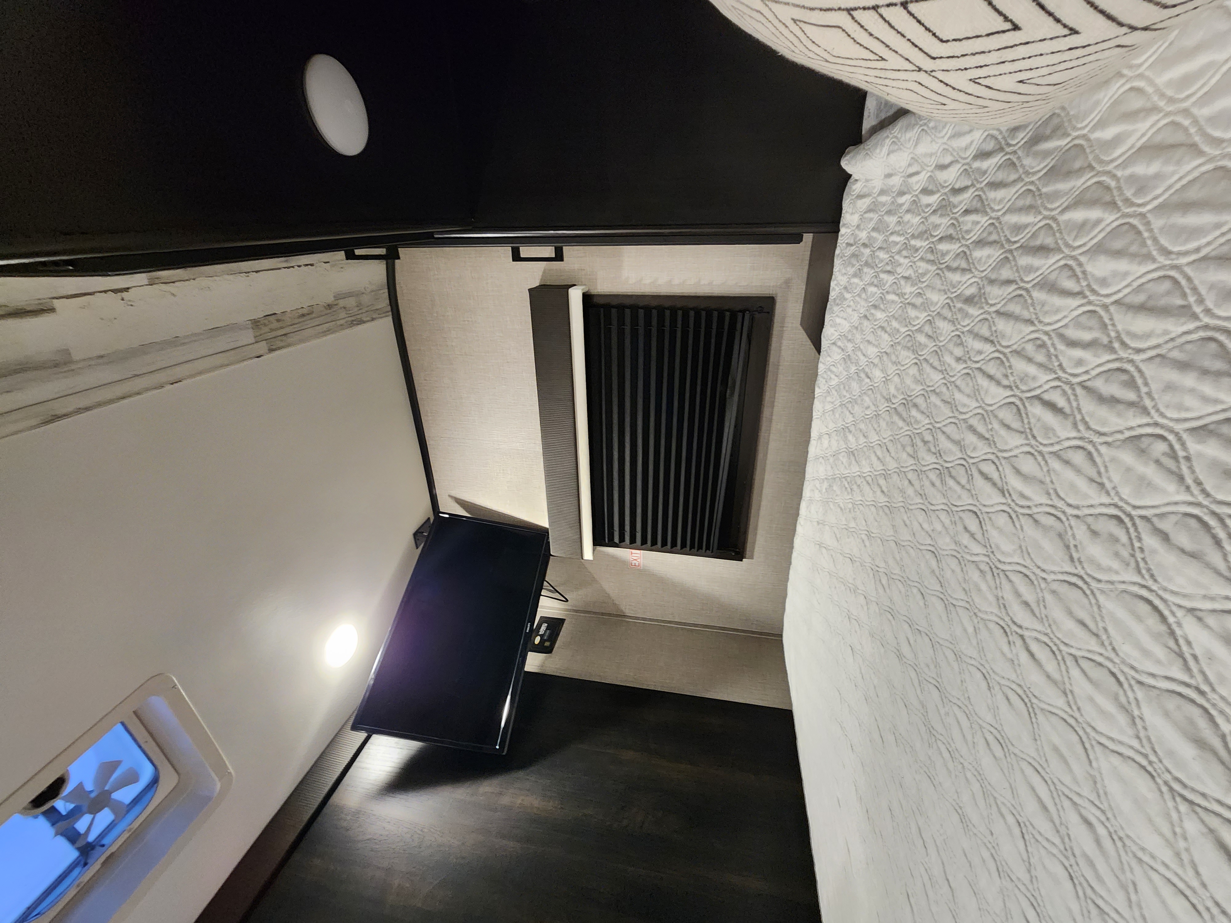 Cozy RV rental bedroom with white quilted bed, wall-mounted TV, and ceiling vent for a comfortable interior.. Jayco Jay Feather 2022