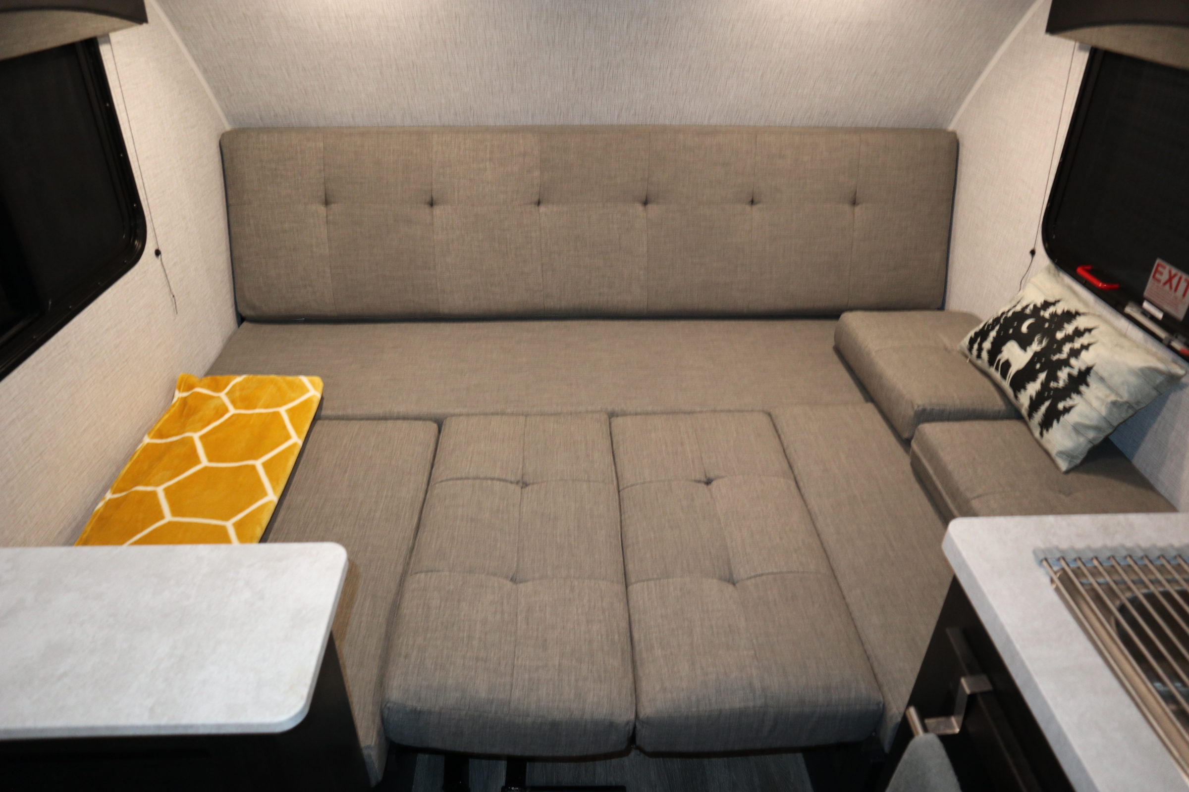RV rental interior: Comfortable, convertible seating transforms into a bed, with a yellow blanket and forest pillow for cozy travels.. Braxton Creek Bushwhacker Plus 2022