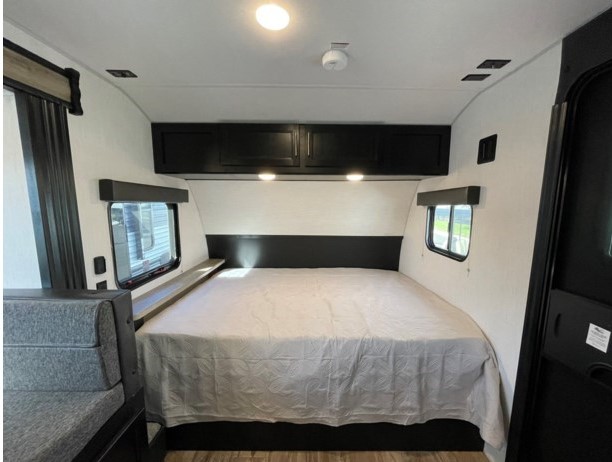 RV rental: Interior of a travel trailer bedroom with a large bed, sleek black overhead cabinets, and side windows.. Forest River Wolf Pup 17JG 2023