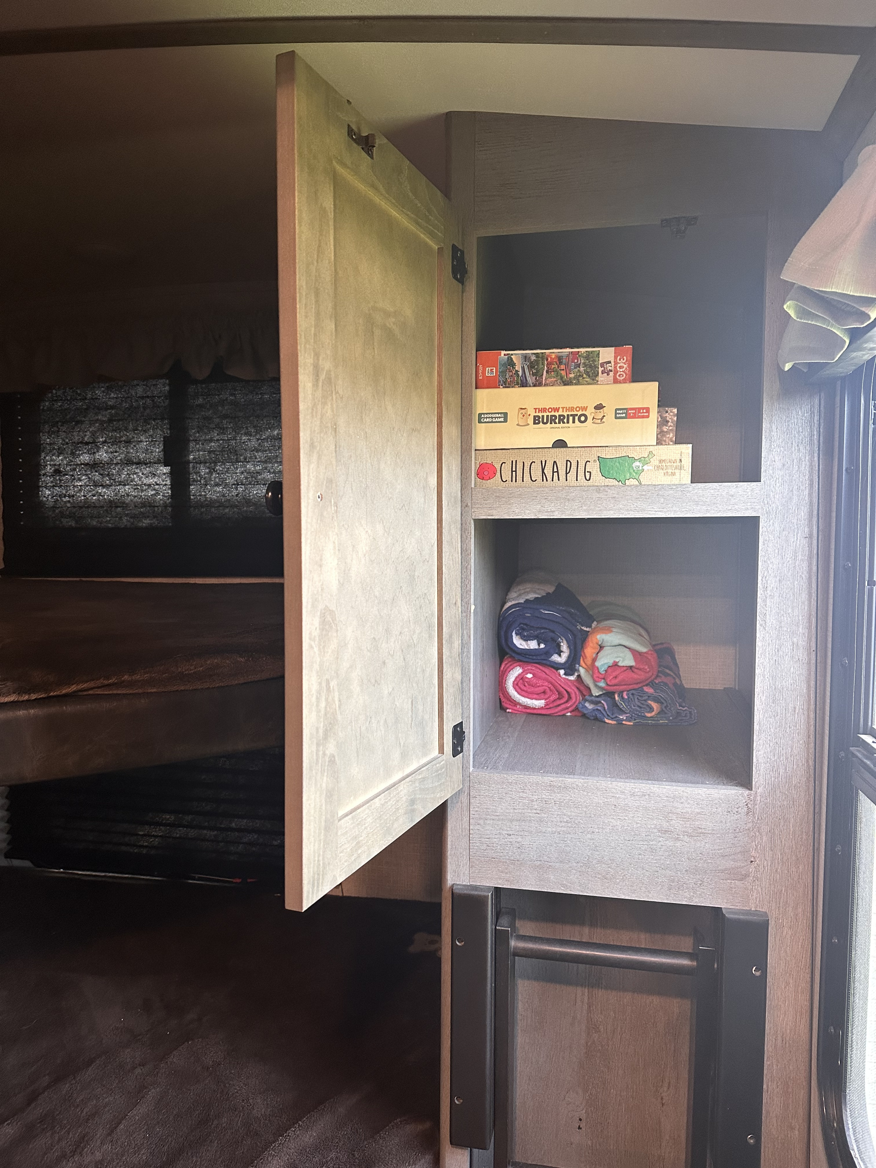 RV rental interior featuring bunk beds, cabinet storage with board games, and rolled towels.. Keystone RV Outback Ultra-Lite 2020