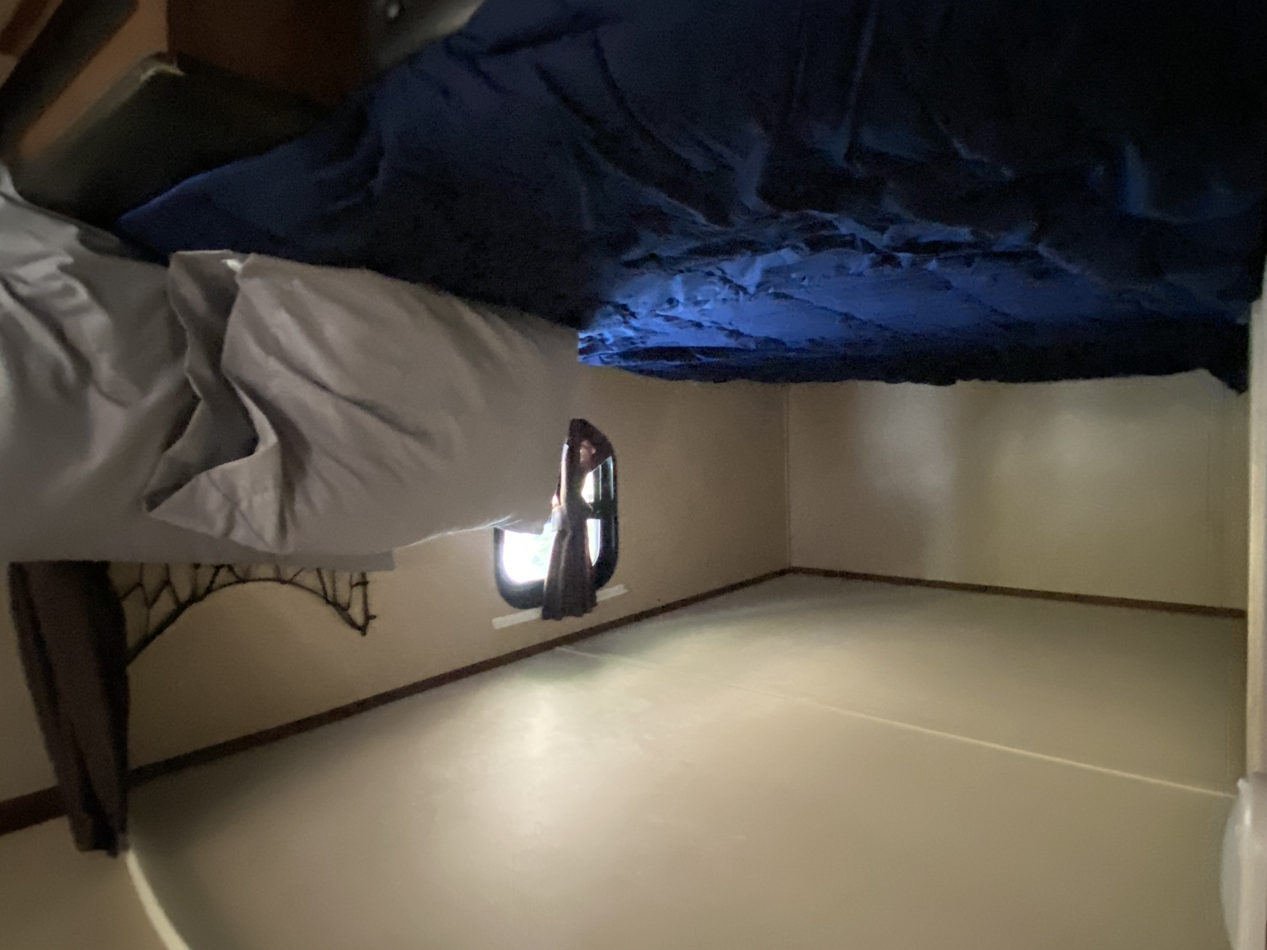RV rental bunk area: blue and gray bedding overhead, with an empty, light-colored floor below and a small window.. Jayco Jay Flight 2015