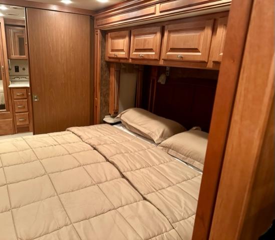 Inside this cozy RV rental: a comfortable bed with neutral bedding, overhead wooden cabinets, and built-in storage solutions.. Phaeton Phaeton Motorhome 2011