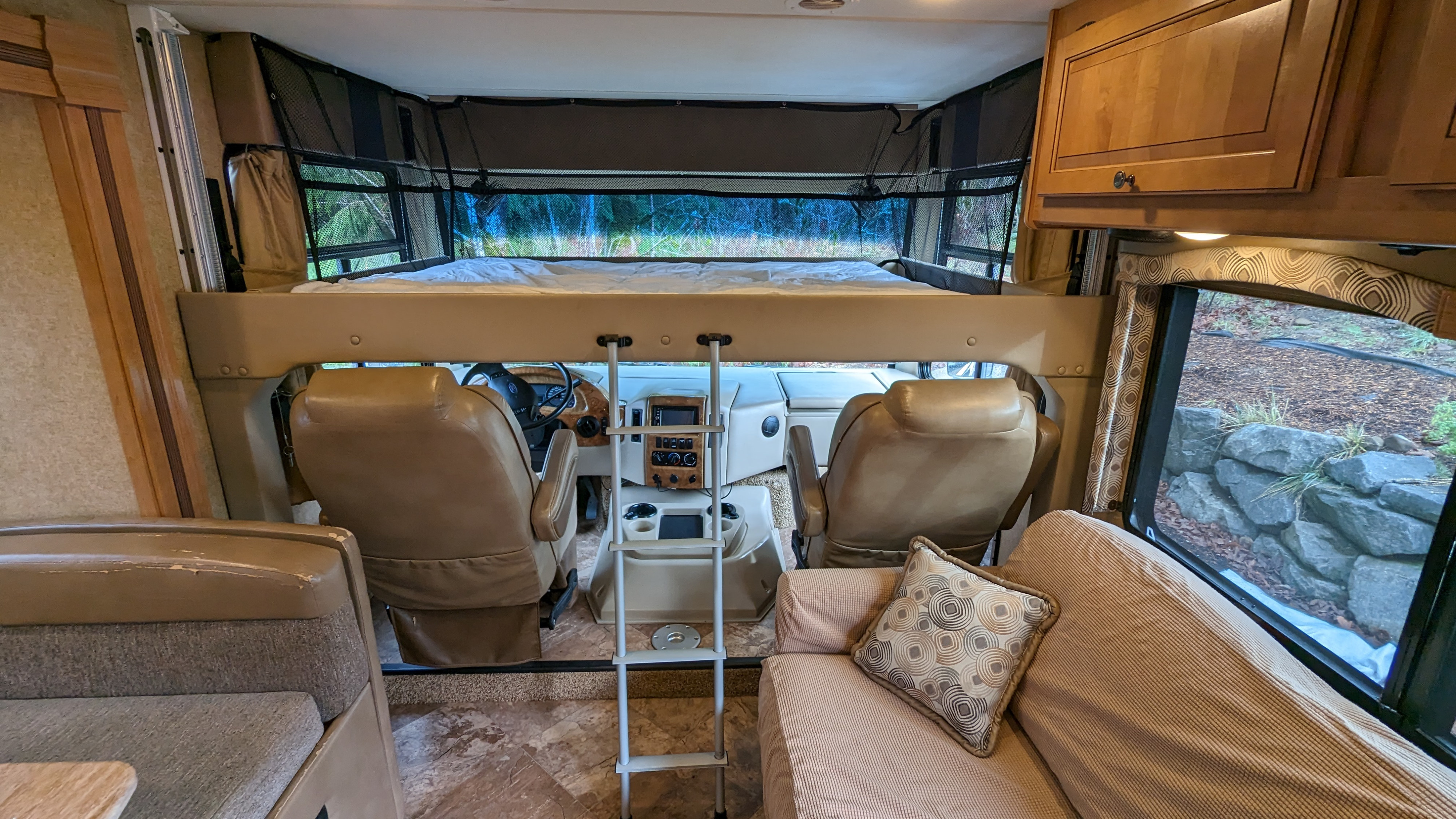 Spacious rv rental interior with over-cab bunk bed, cockpit, and living area, perfect for comfortable travel accommodations.. Thor Windsport 2016
