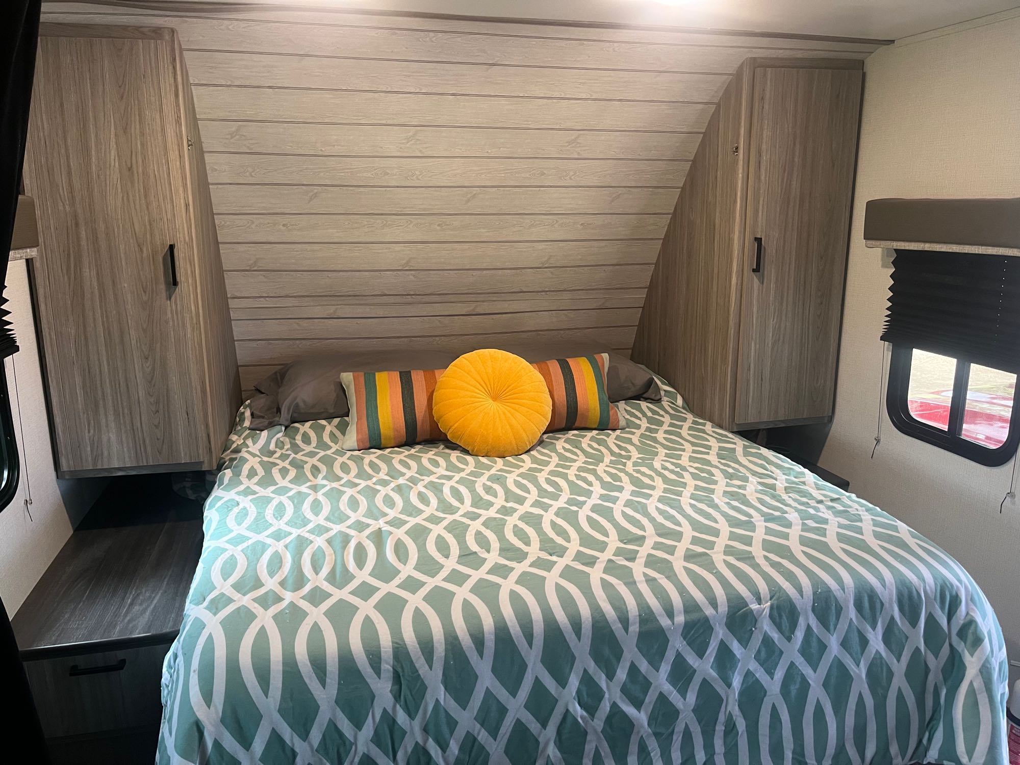 Comfortable RV rental bedroom with teal patterned comforter, bright pillows, and ample storage cabinets for your travels.. Keystone RV Passport SL 2022