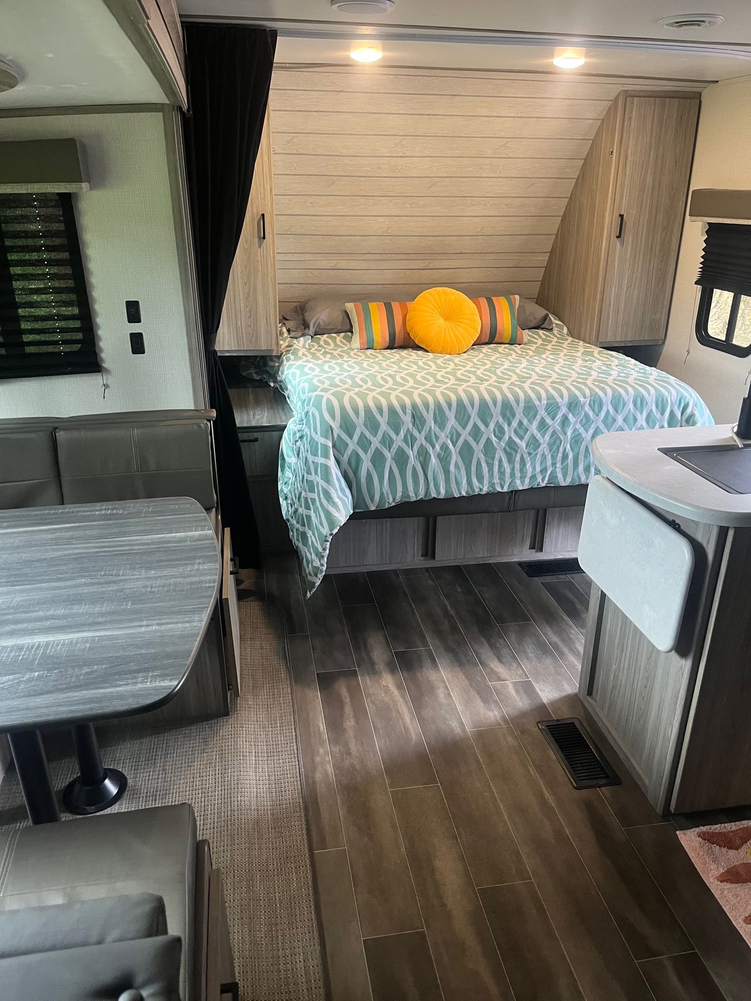 Modern RV rental interior with a cozy bed, vibrant pillows, and a compact dinette space.. Keystone RV Passport SL 2022