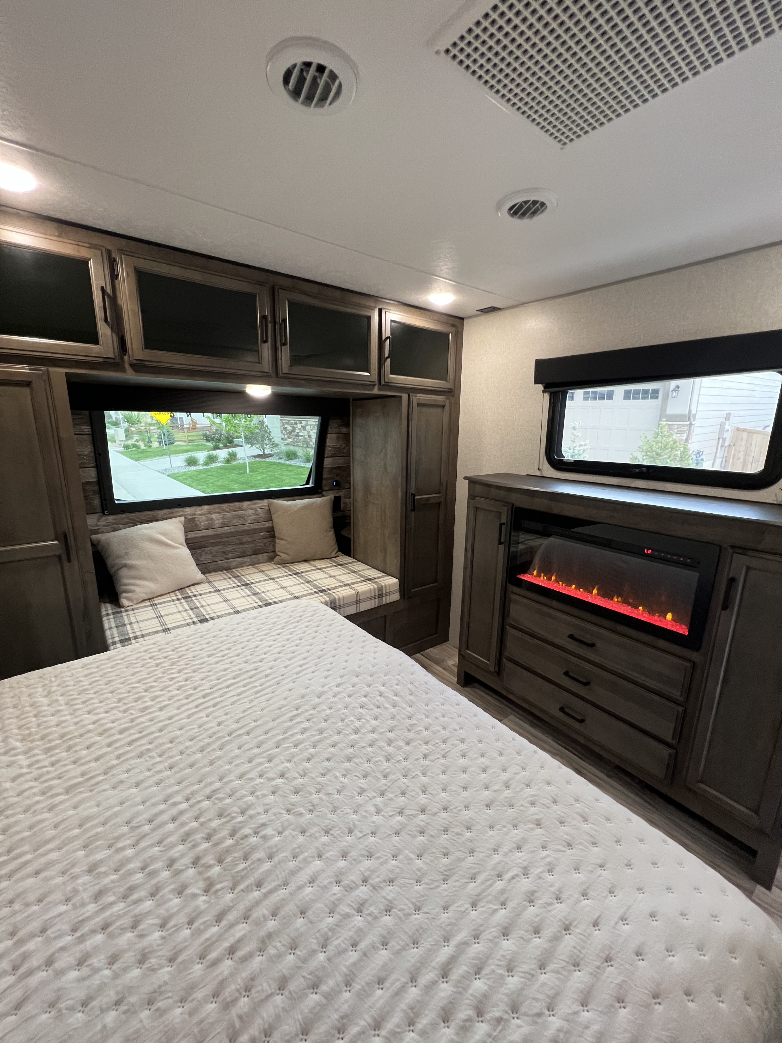 RV rental bedroom with a quilted bed, window bench, and built-in electric fireplace. A cozy interior for your adventure.. Sport Trek Touring Edition 2023