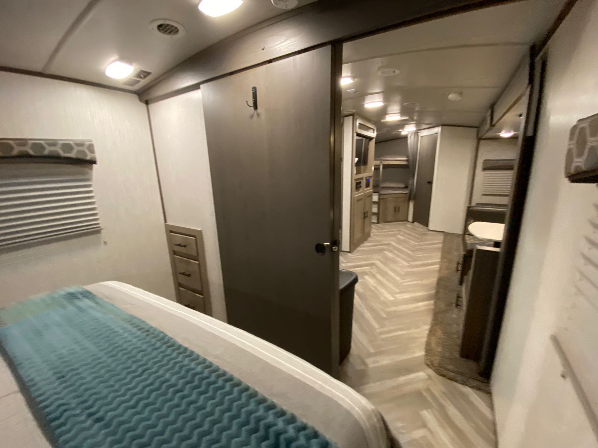 Spacious RV rental showcasing a cozy bedroom with bed & dresser, opening to a hallway with bunk beds. Ideal for family trips.. Shadow Trailers 277BHS 2020