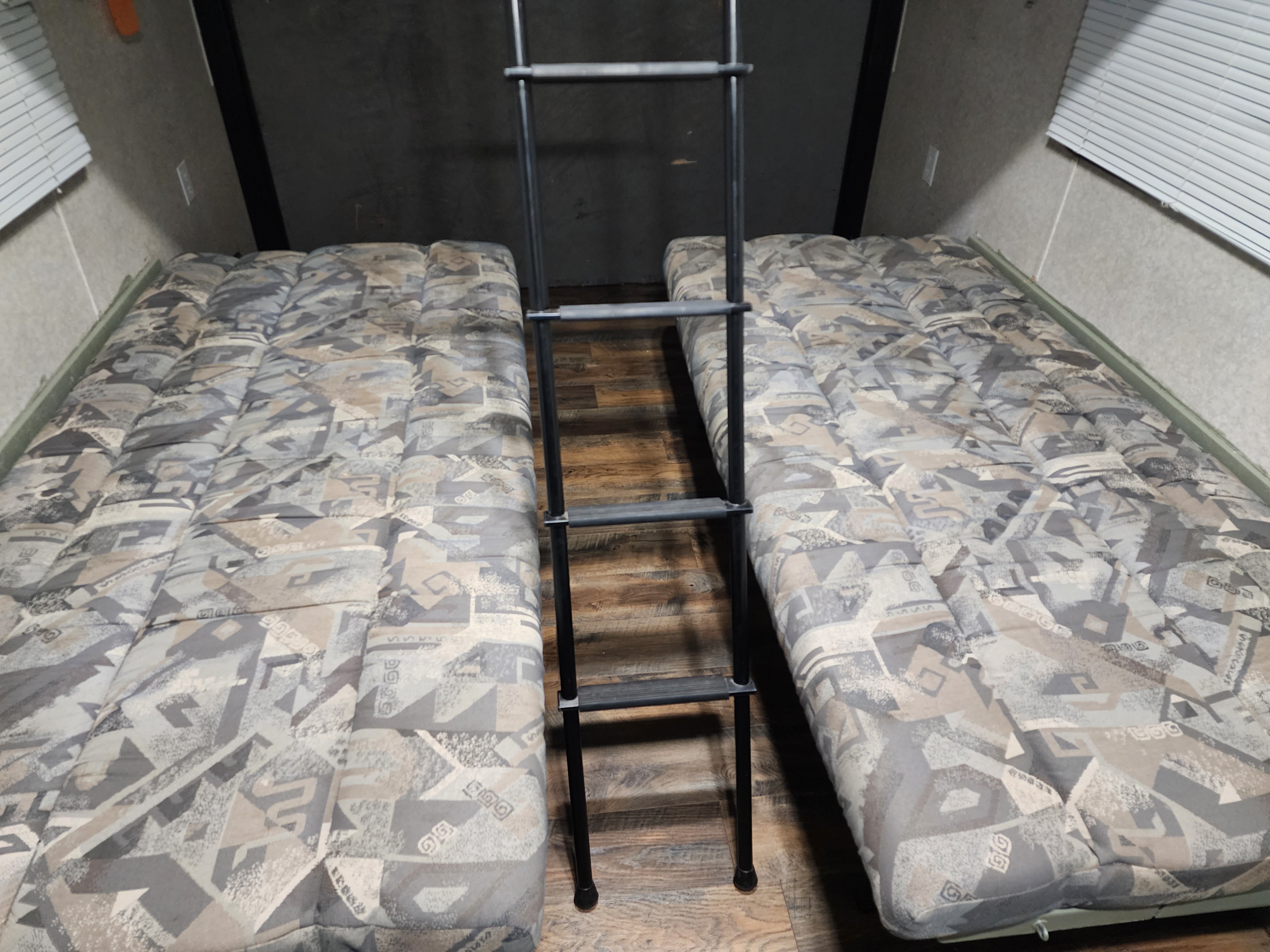 Comfortable RV rental sleeping area with two patterned mattresses and a sturdy ladder in the center.. Carson Trailer Titan 2004