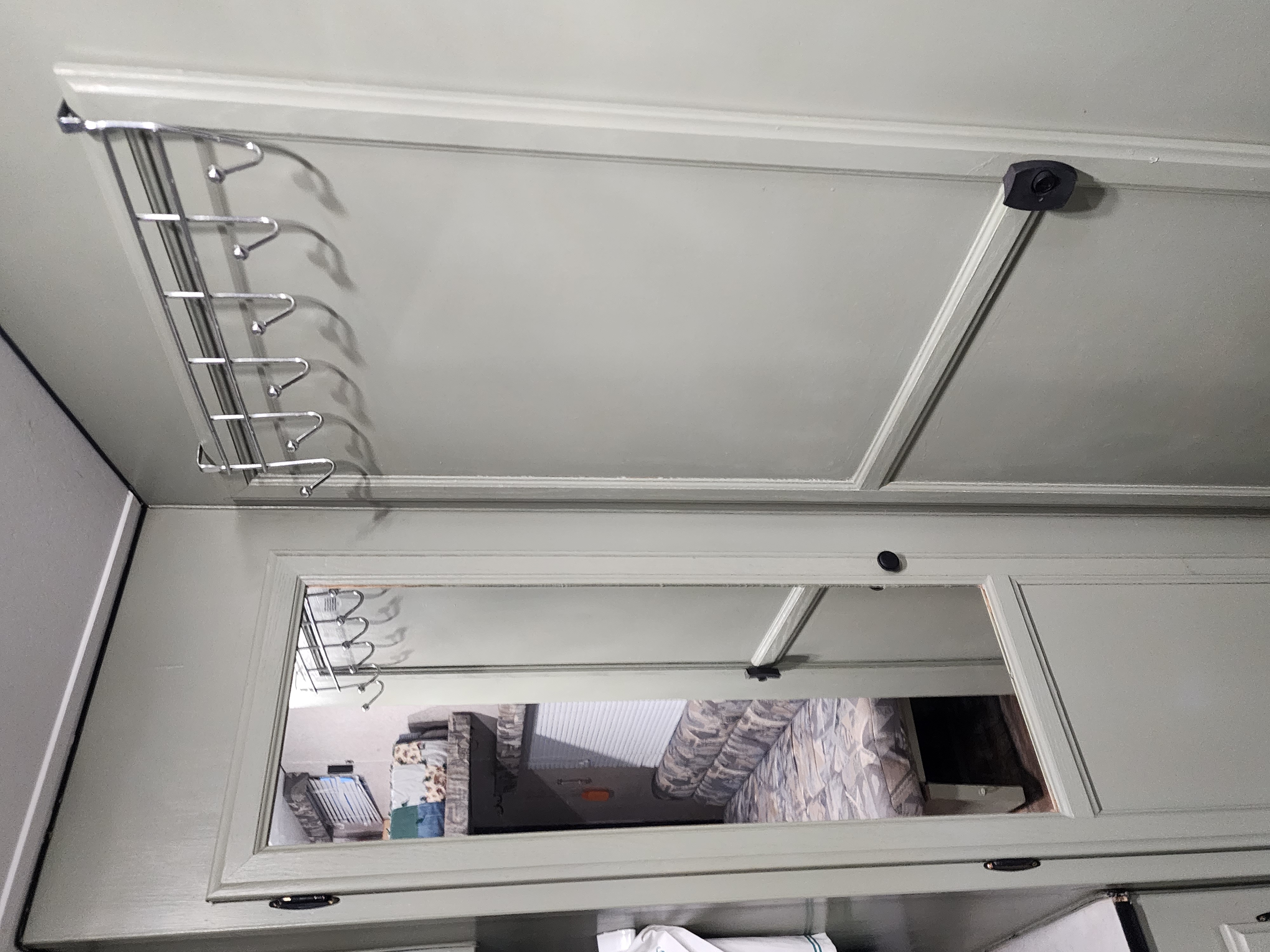 RV rental: Upper cabinet with a mounted metal rack and hooks, reflecting the patterned interior below.. Carson Trailer Titan 2004