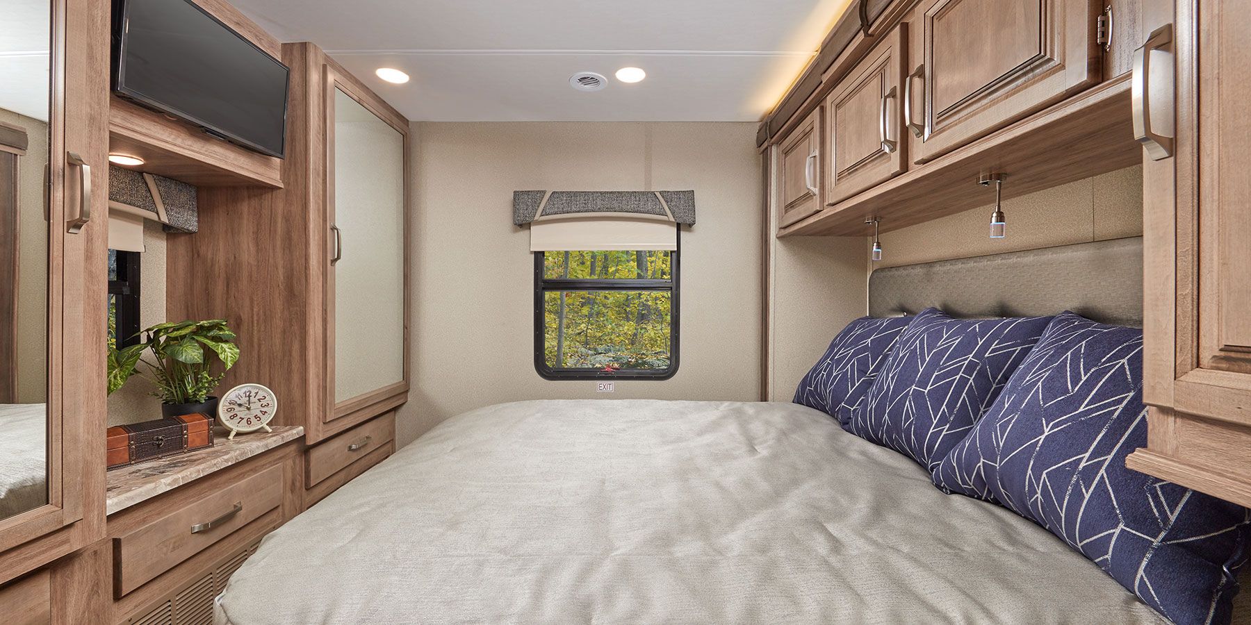 Cozy RV rental bedroom featuring a comfy bed, overhead cabinets, TV, and a window with a nature view.. Jayco Greyhawk prestige 30XP 2020