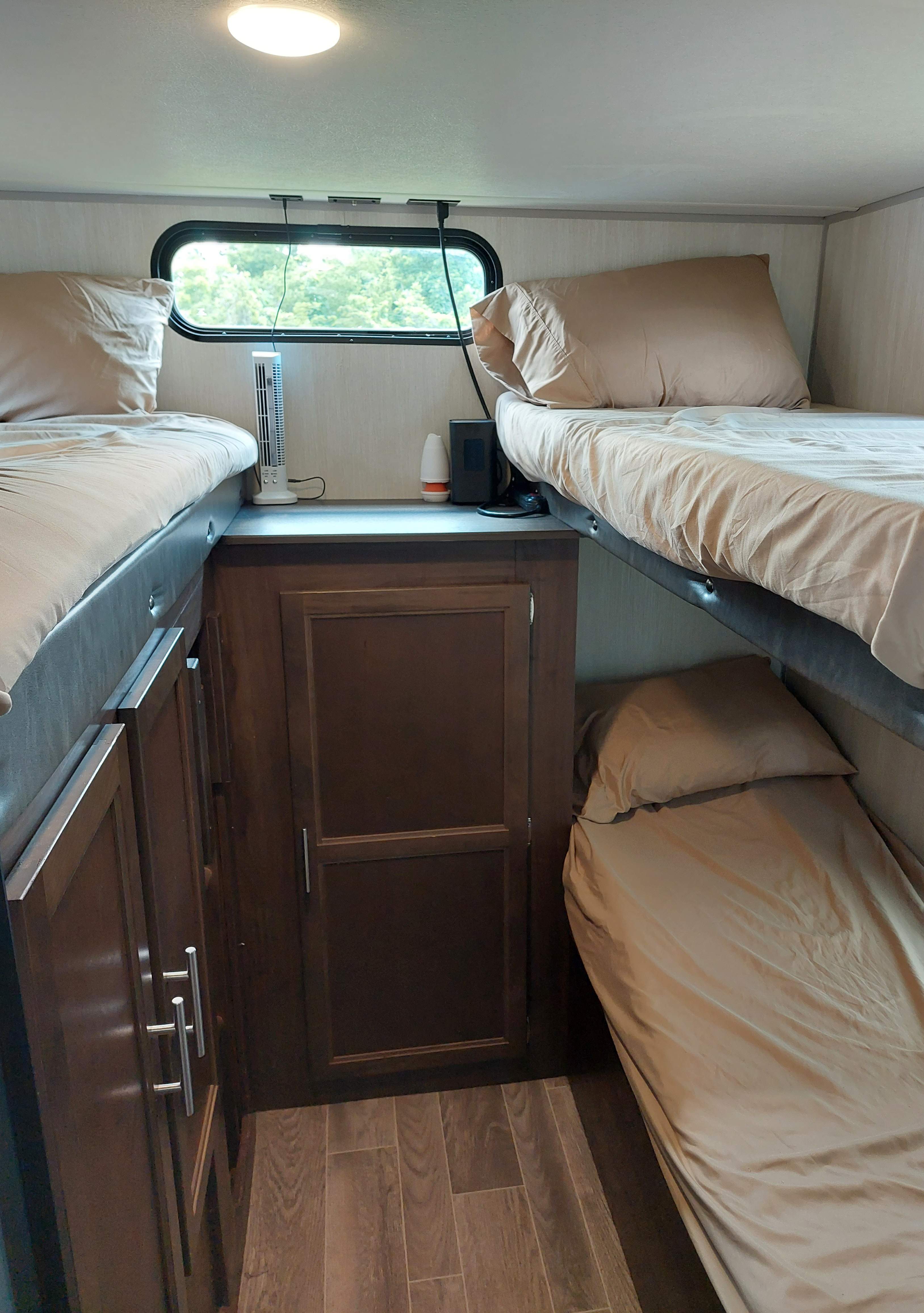 Cozy RV rental interior with triple bunk beds, a fan, and storage cabinets for comfortable travel.. Forest River Cherokee Grey Wolf 2019