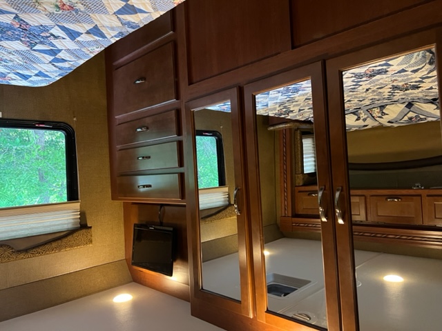 Experience our RV rental! Cozy bedroom features mirrored closets, drawers, TV, and scenic window views.. Ford Freedom Elite 2016