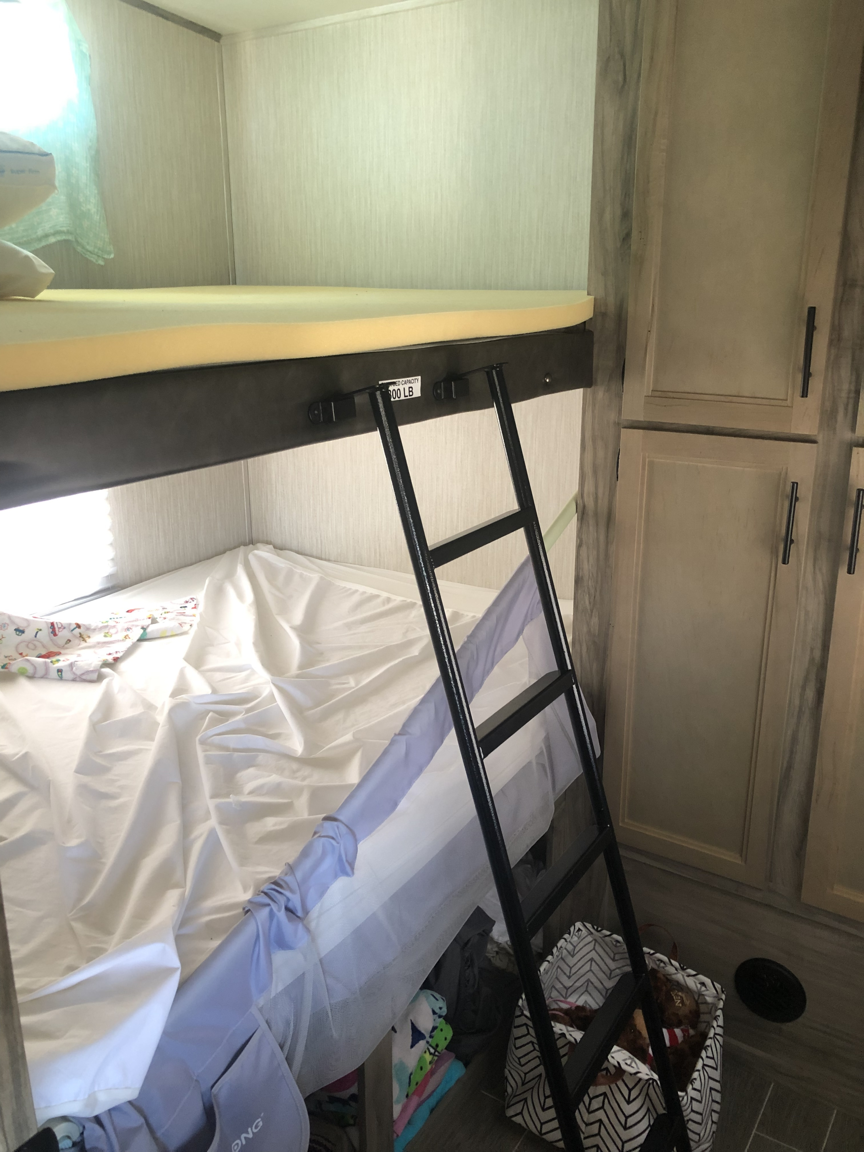 RV rental interior: cozy bunk beds with ladder (300 LB capacity) and cabinets, ready for family adventures.. Forest River Cherokee Arctic Wolf 2020
