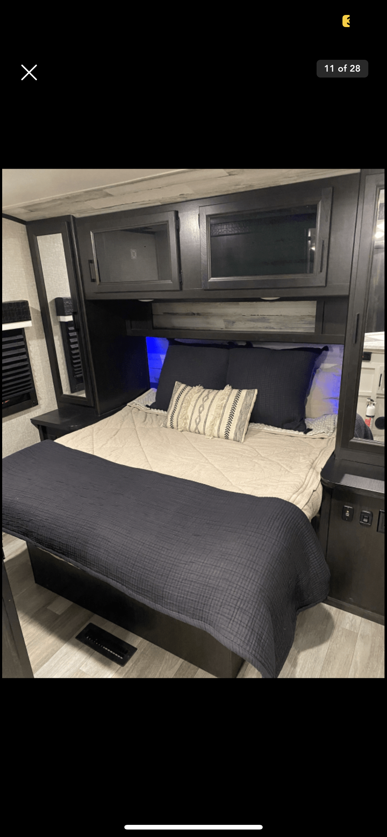 Cozy RV rental bedroom with blue accent lighting, a comfortable bed, and dark wood-look cabinetry. Perfect for travel.. Jayco Jay Feather 2022