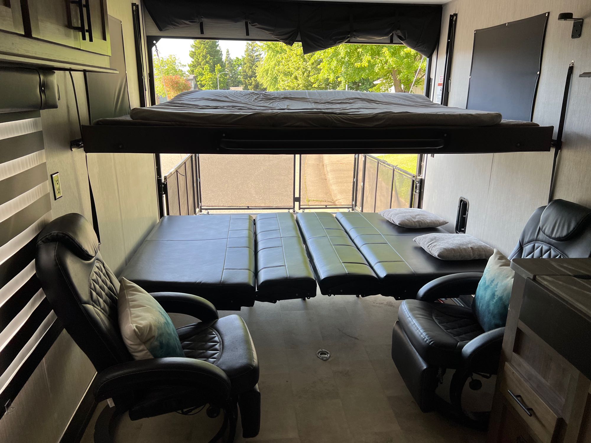 Spacious RV rental interior featuring convertible bunk beds, modular seating, and recliners, with an open ramp door view.. Rogue Vengeance 2021