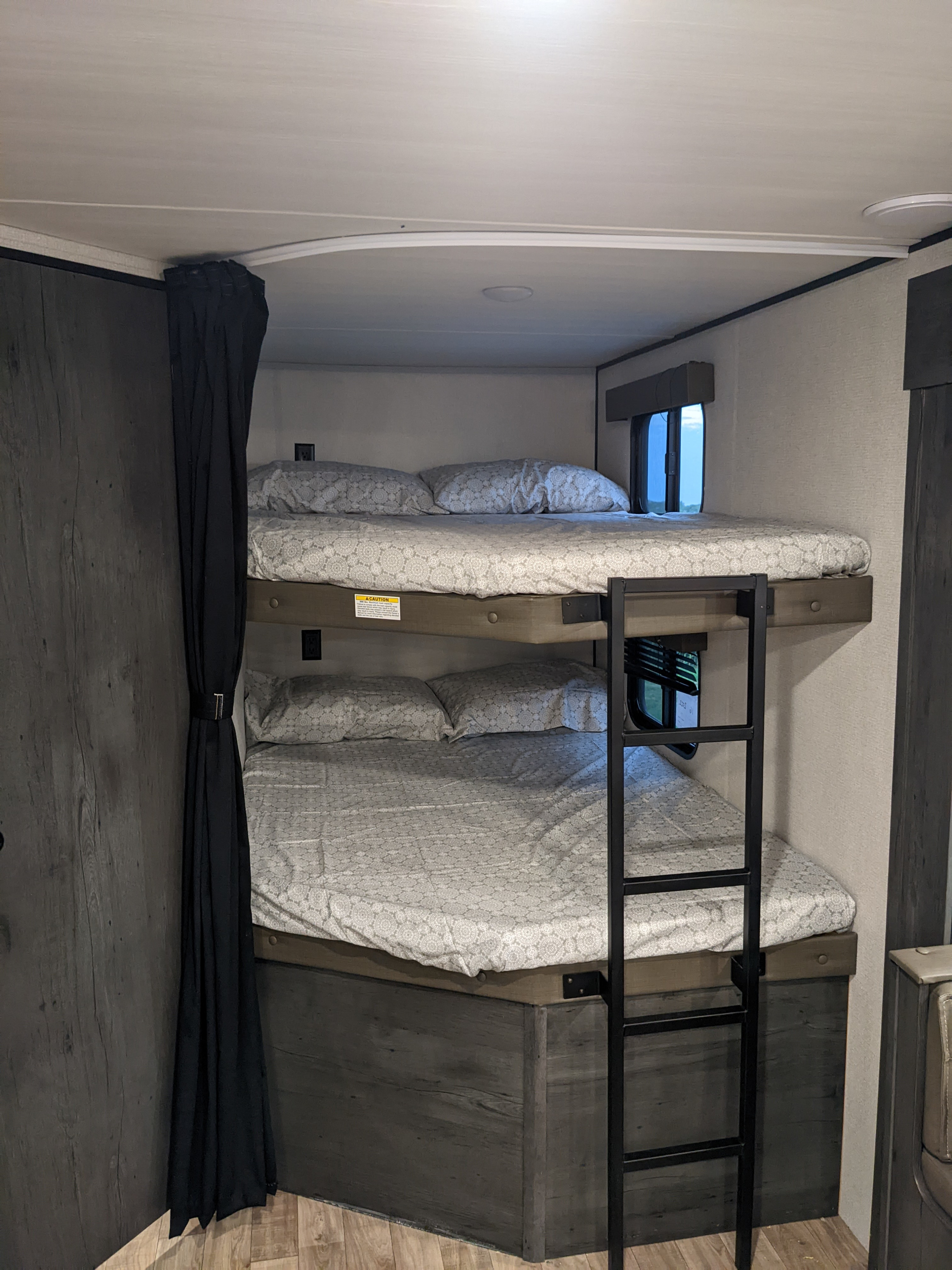 Cozy RV rental bunk beds with a ladder, privacy curtain, and windows, ready for your next adventure.. Keystone RV Hideout 2022