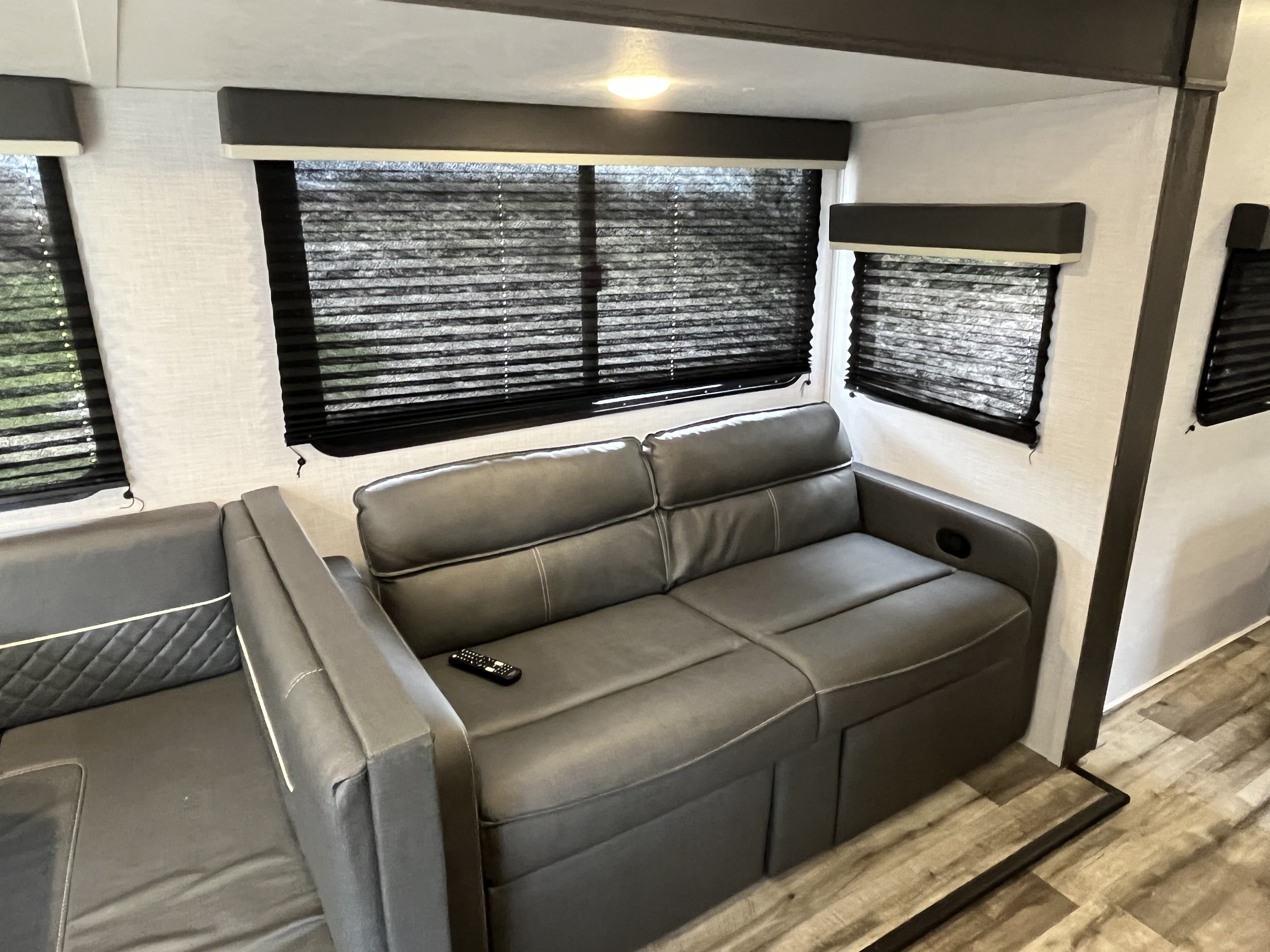 Relaxing RV rental interior: gray sofa, pleated window blinds, and light wood-look floor.. Dutchmen Coleman Light 2022