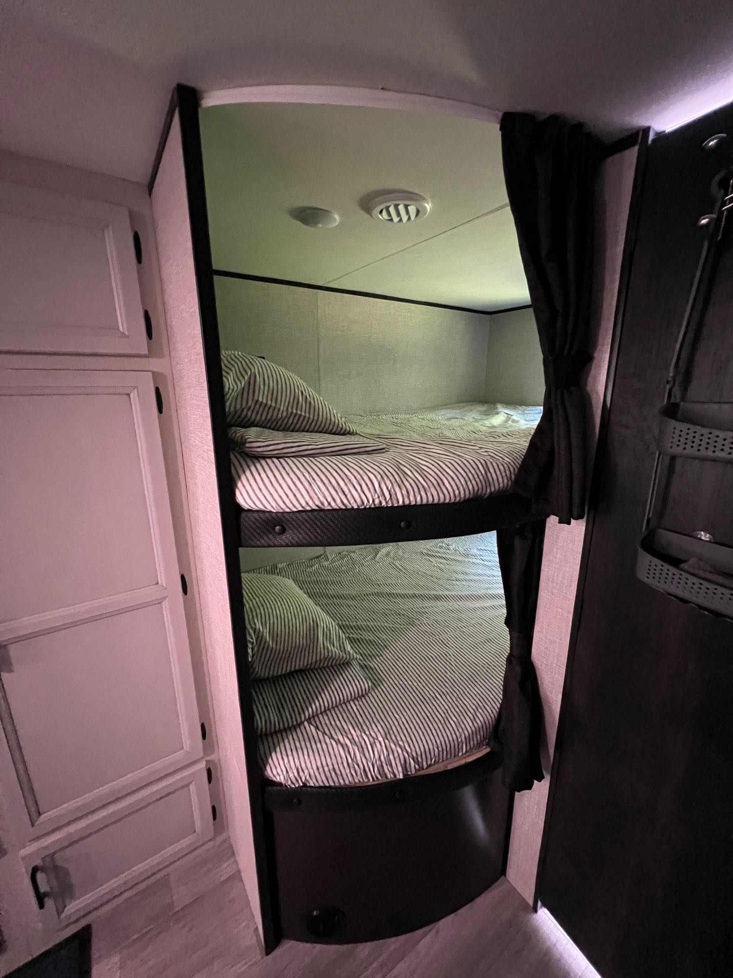 Inside an RV rental: view of neatly made bunk beds with striped bedding and curtains, offering a compact sleeping space.. Jayco Jay Flight SLX 2022