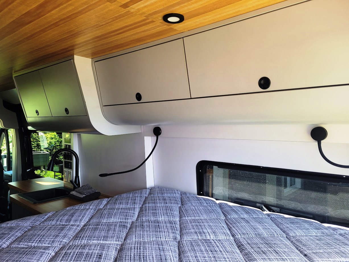 Modern **RV rental** interior with bed, overhead storage, and kitchen.. Promaster 3500 EXT 2022