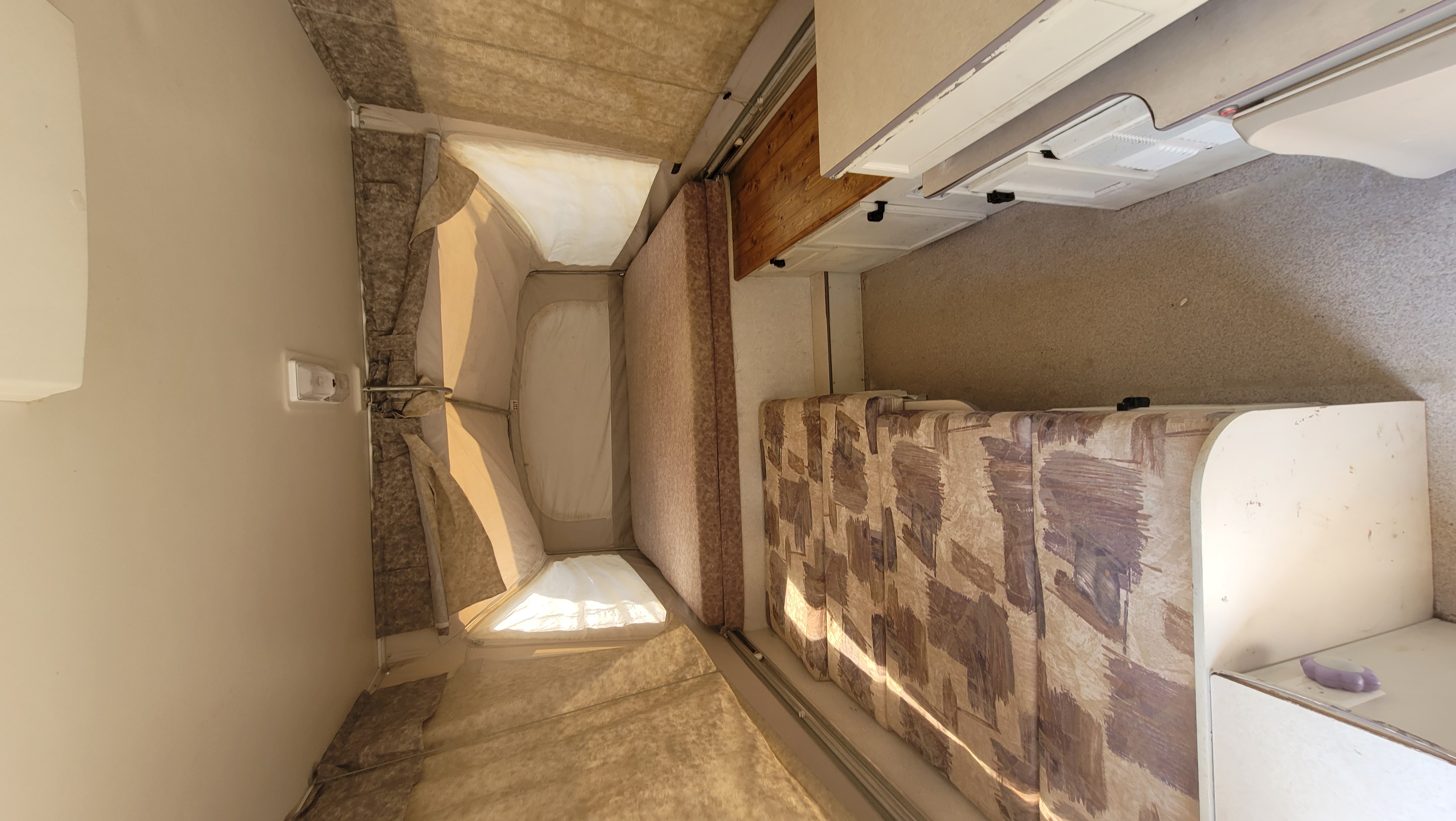 RV rental pop-up camper interior: canvas bed area, sofa seating, and compact kitchen space.. Jayco Heritage 2000