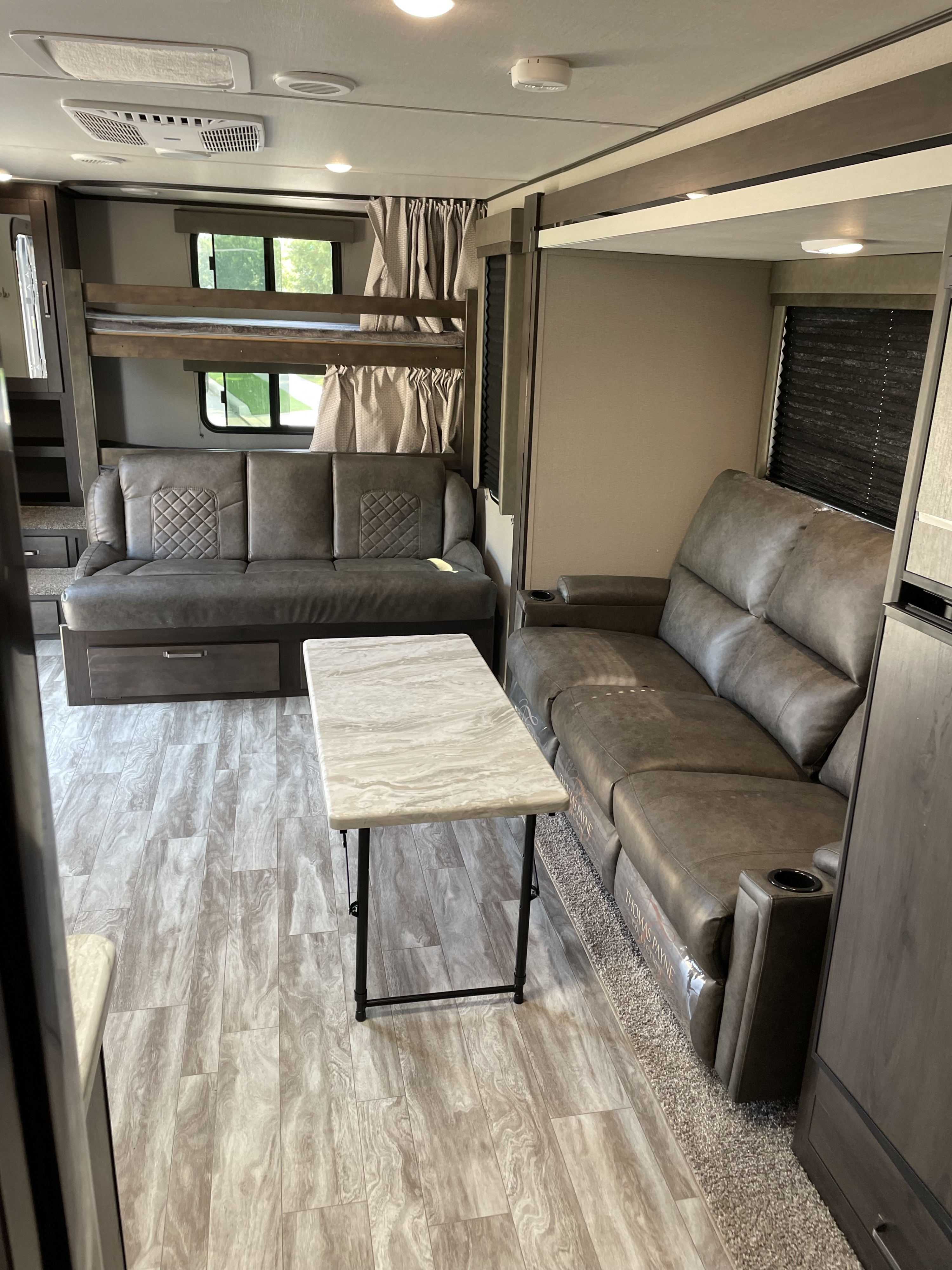 Cozy RV rental interior with bunk beds, two comfortable sofas, and a portable table for relaxing family trips.. Grand Design Transcend Xplor 2020