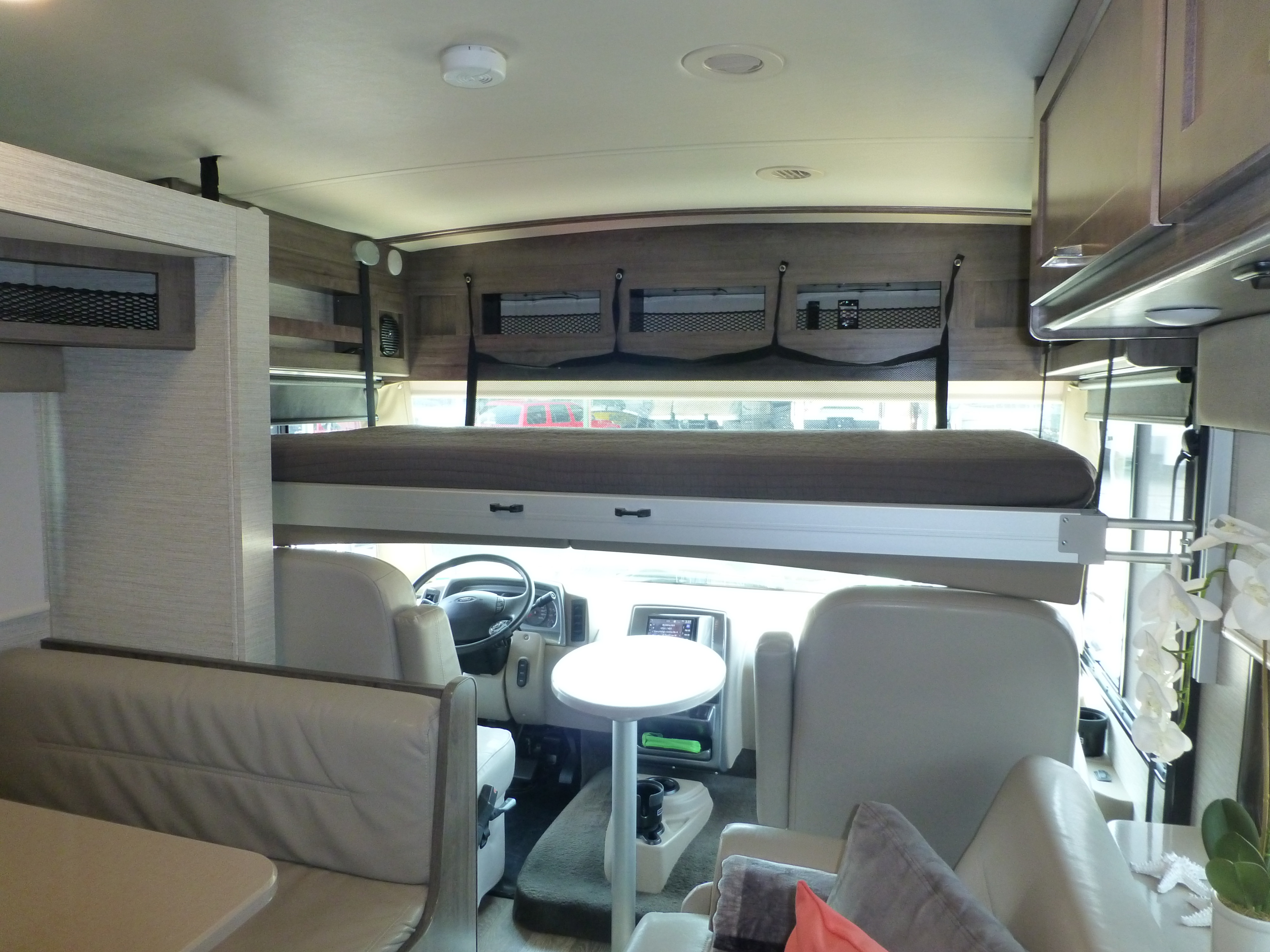 RV rental interior: overhead bunk, driver's cockpit, dinette, and ample storage. Your mobile adventure home.. Winnebago Vista 2020