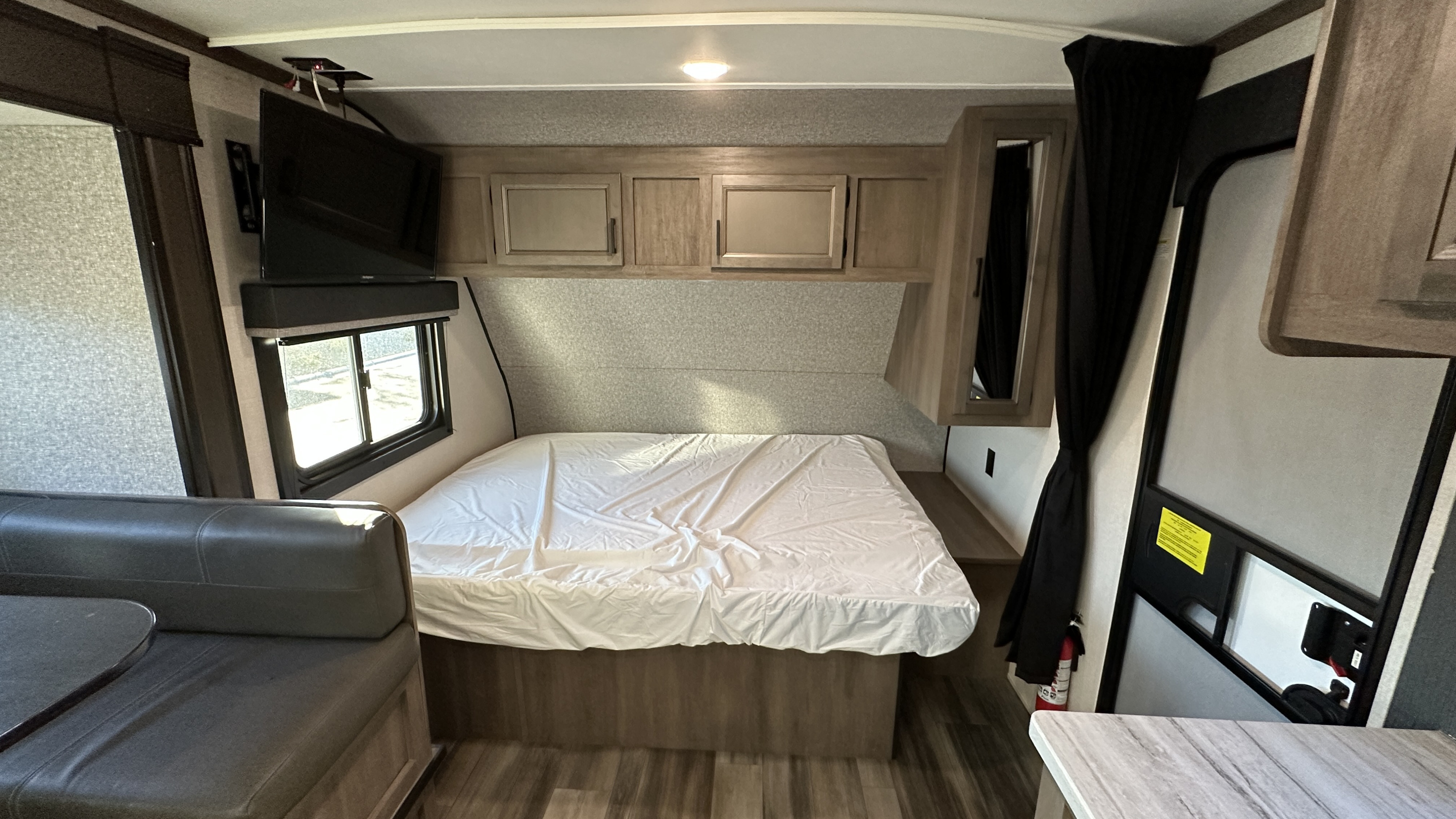 View inside an RV rental with a bed, small seating area, TV, and cabinets, offering a comfortable travel setup.. Starcraft Autumn Ridge 2022