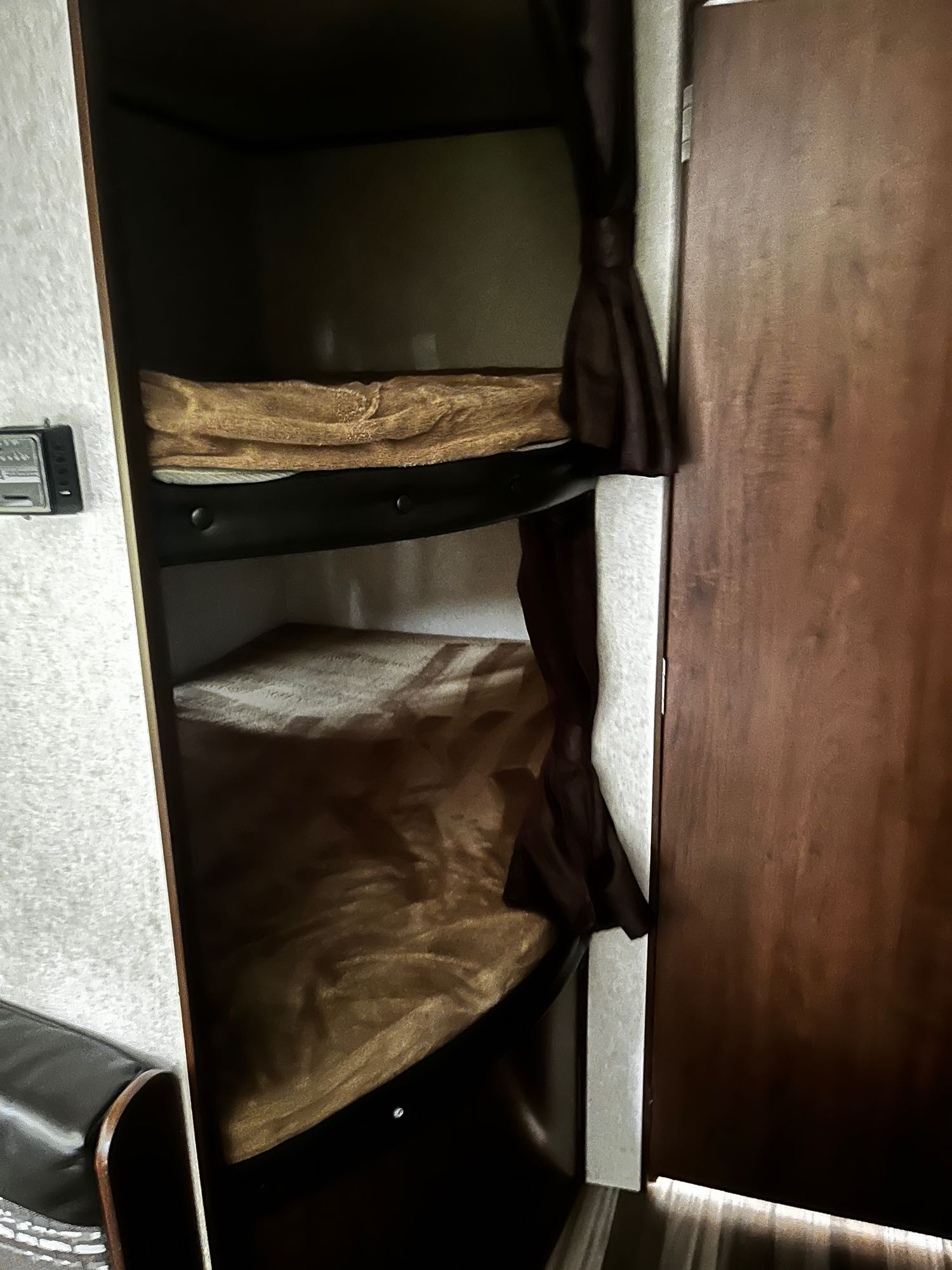 Interior view of an RV rental showing two stacked bunk beds with brown bedding and privacy curtains for a cozy sleep.. Jayco Jay Flight 2017