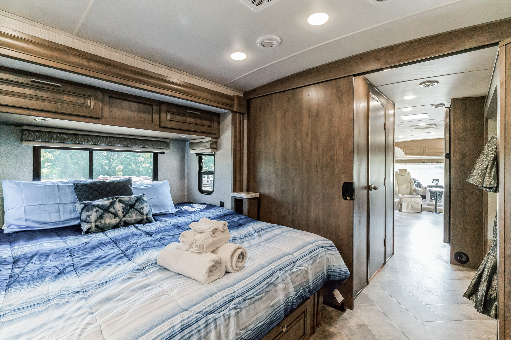 Spacious RV rental bedroom with cozy blue bedding, ideal for comfortable travel. See the inviting interior of this motorhome.. Forest River Georgetown 36B5 2020