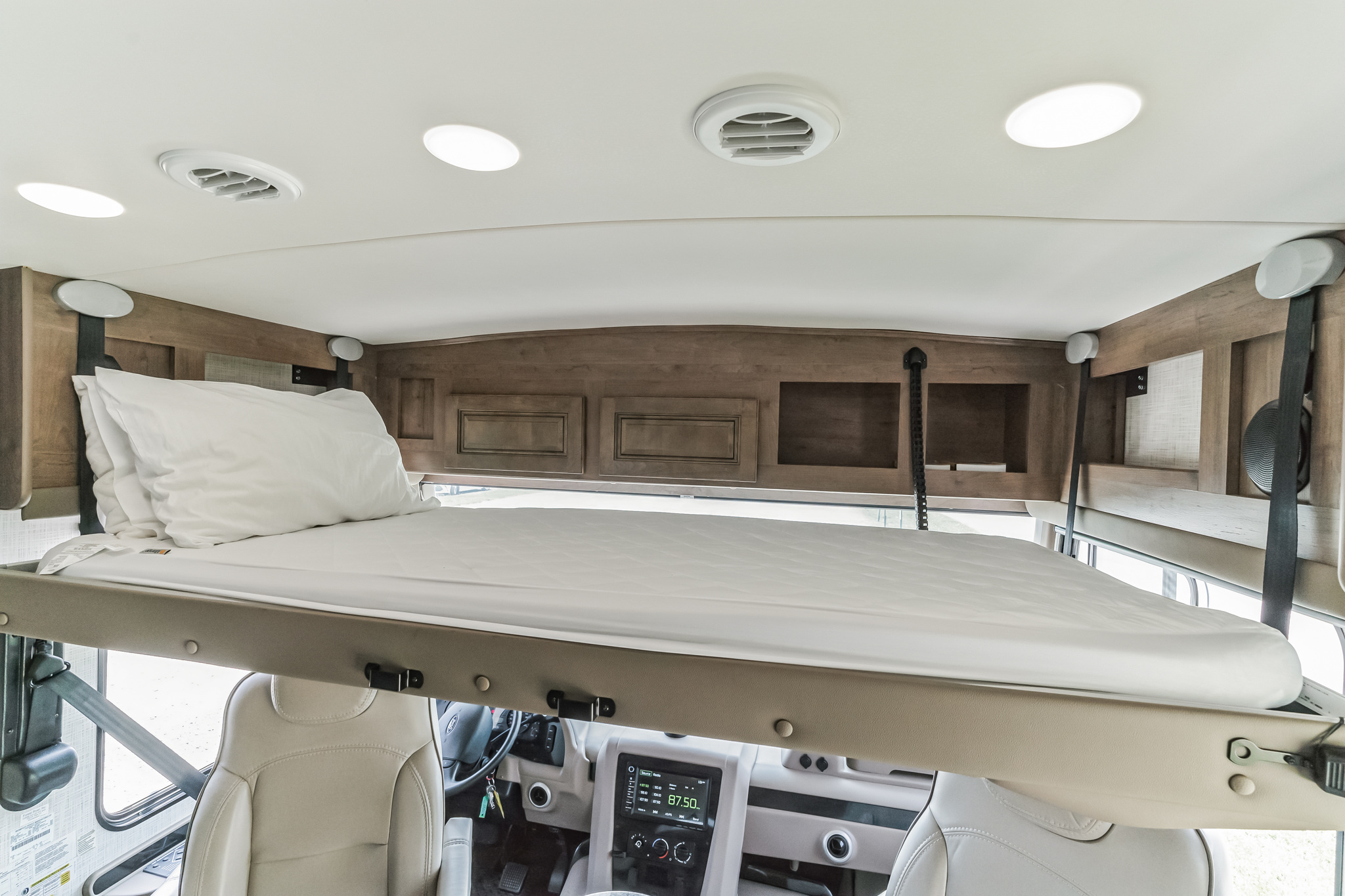 Spacious RV rental interior featuring a comfortable drop-down bed positioned above the front seats and dashboard.. Forest River Georgetown 36B5 2020