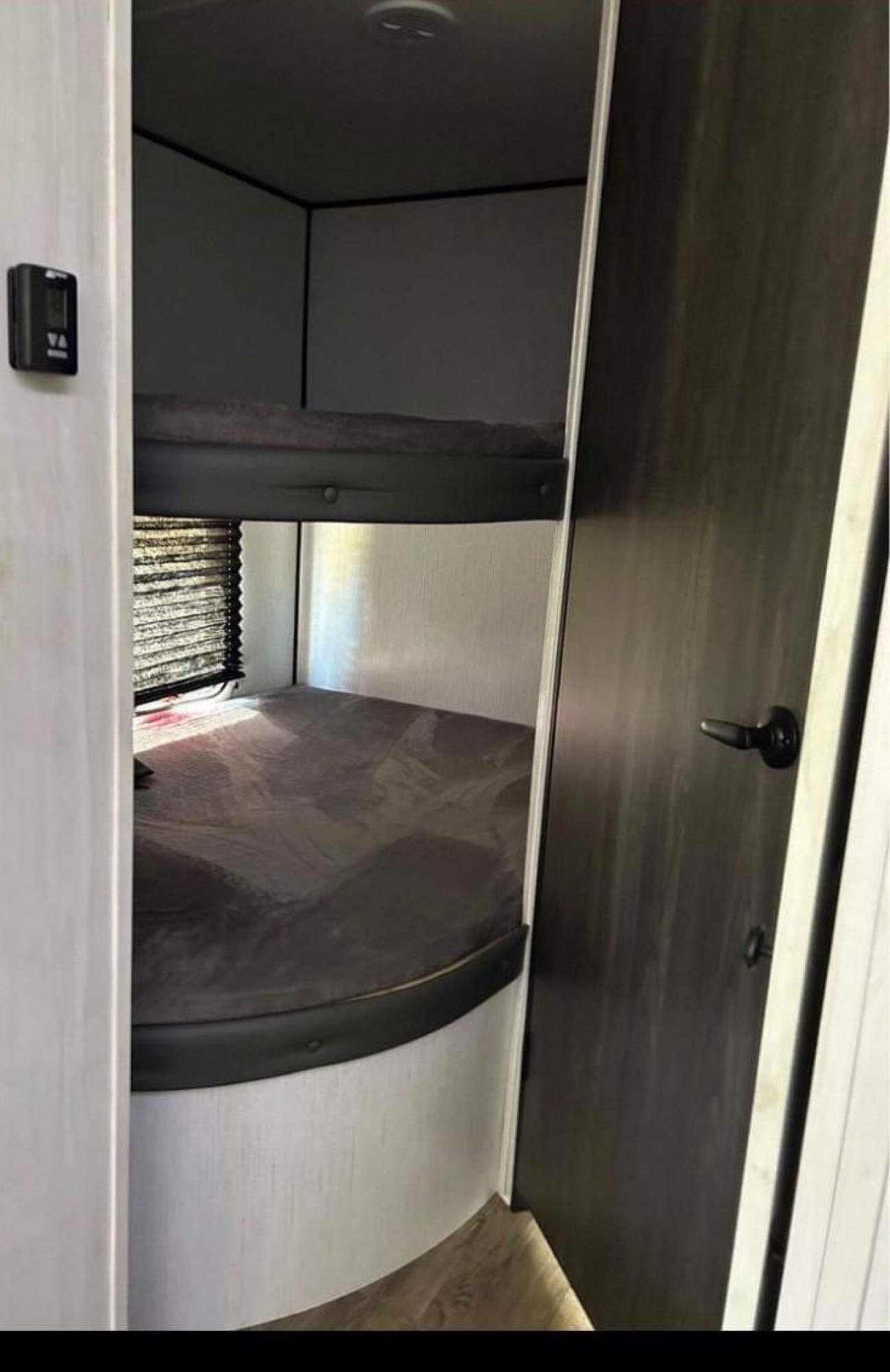 RV rental: Compact bunk bed area with lower mattress in plastic, window blinds, control panel, and a dark privacy door.. Heartland RVs Trail Runner 2022