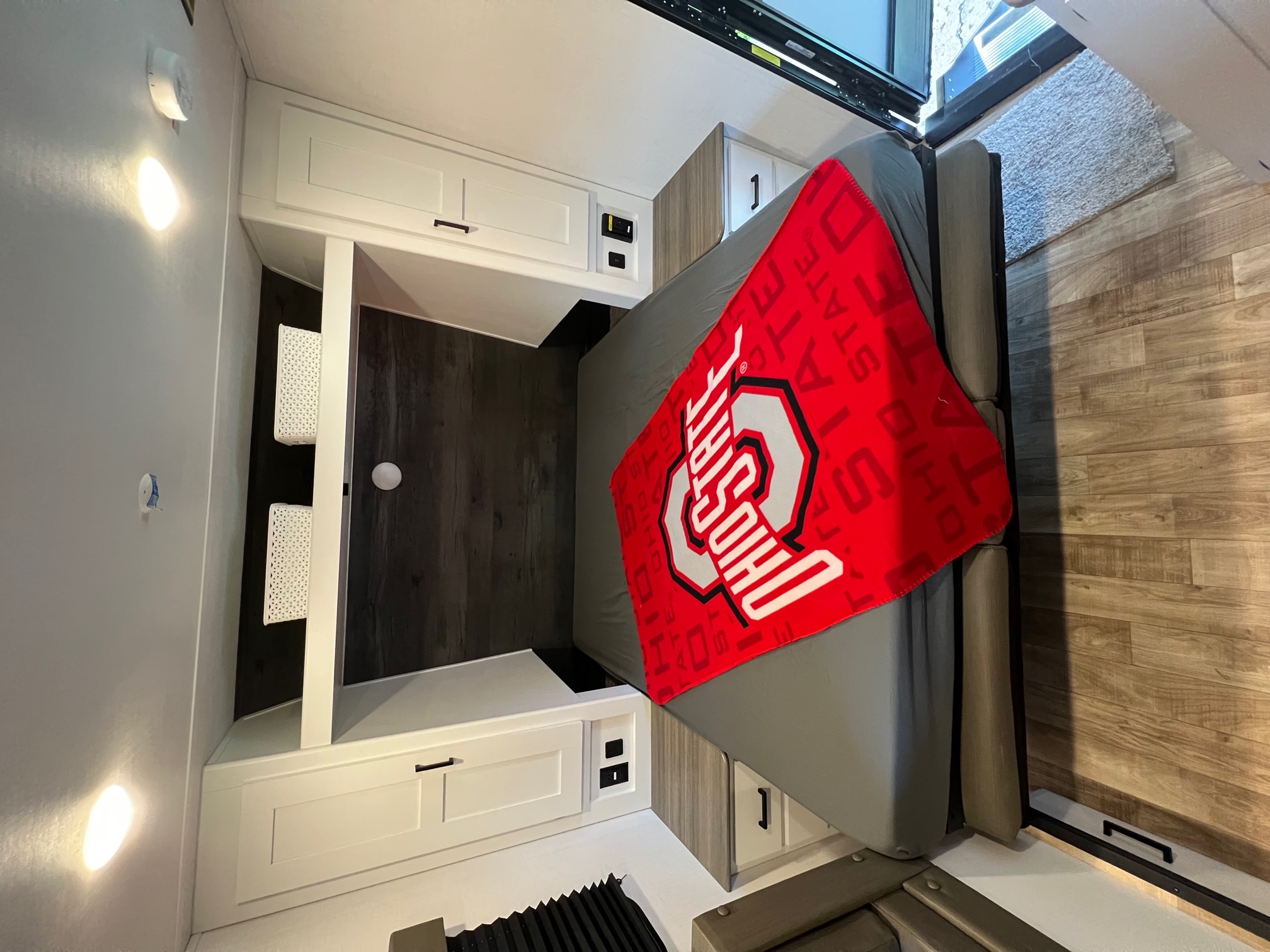 Modern RV rental bedroom with Ohio State blanket, built-in cabinets, and charging ports.. Hideout 181BH 2023