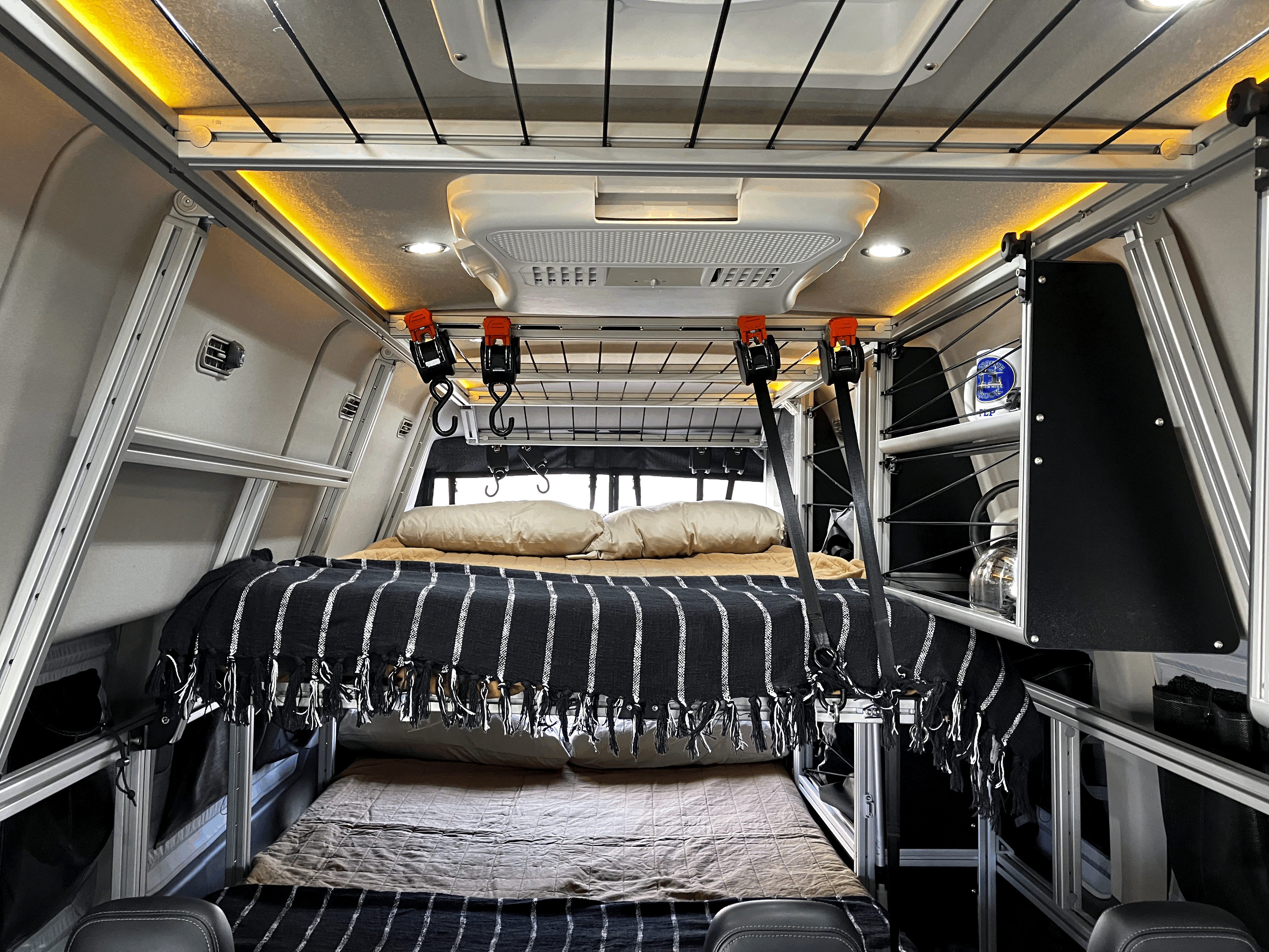 This RV rental's cozy interior features a two-tier bunk bed, modular storage, and ambient lighting, ideal for comfortable travel.. Ford Transit Custom 2022