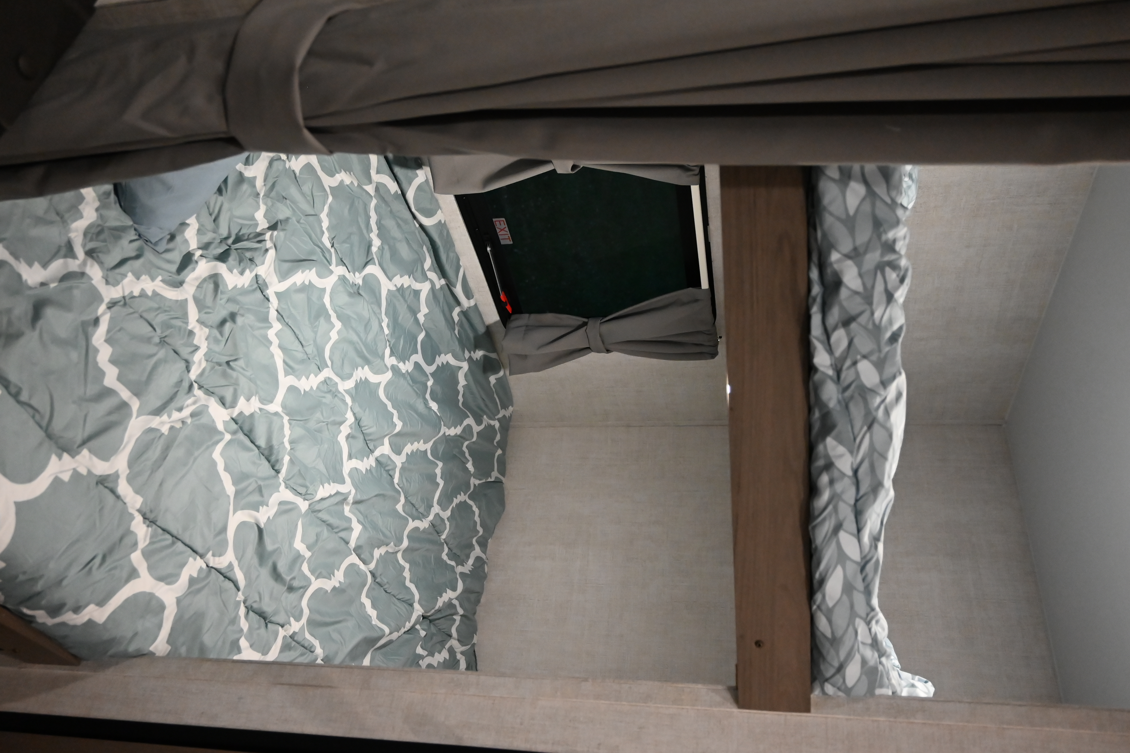 Cozy RV rental sleeping area featuring patterned bedding, privacy curtains, and an emergency exit window.. Gulf Stream Friendship 2022