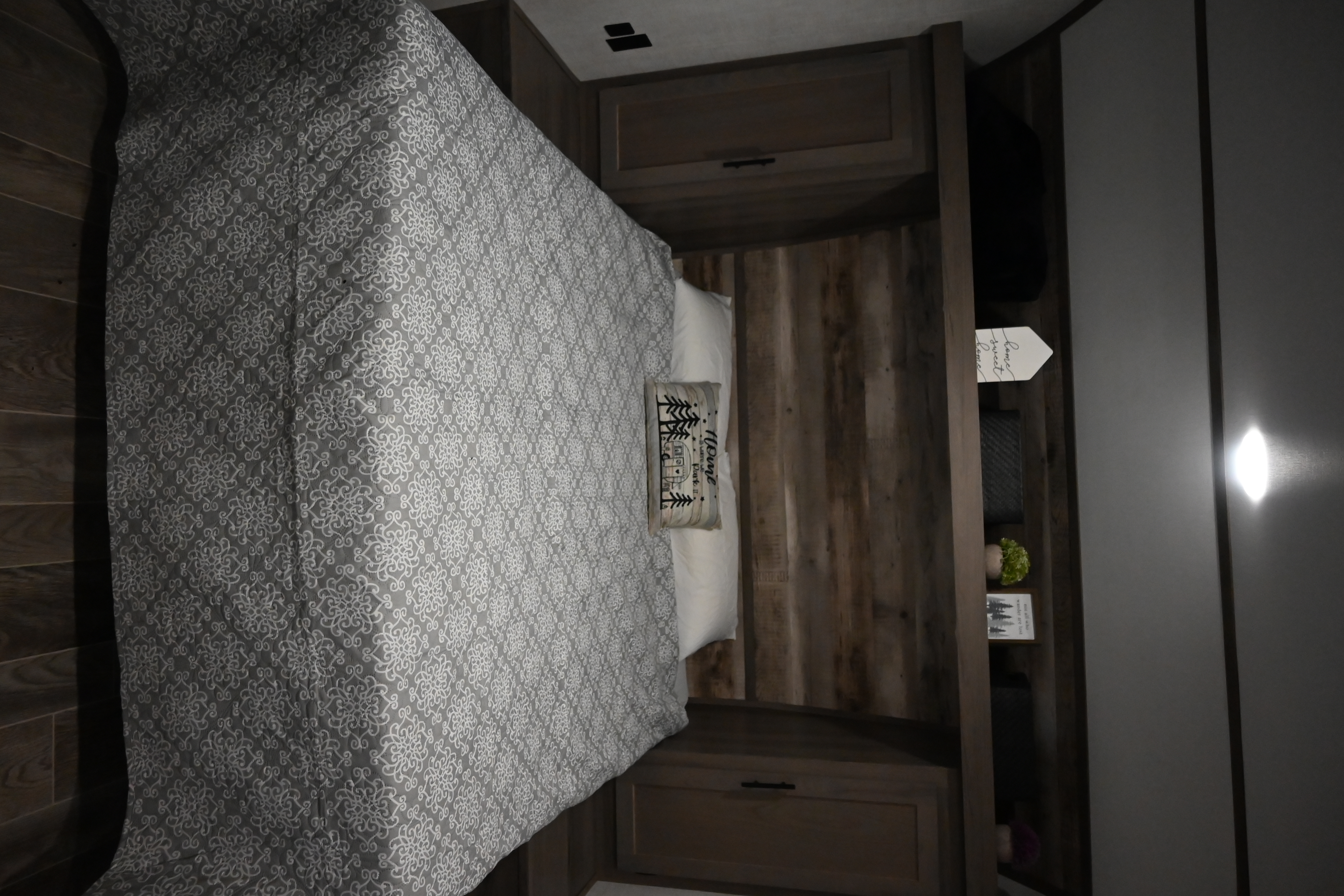 Cozy RV rental bedroom featuring a patterned comforter, decorative pillow, built-in cabinetry, and rustic decor.. Gulf Stream Friendship 2022