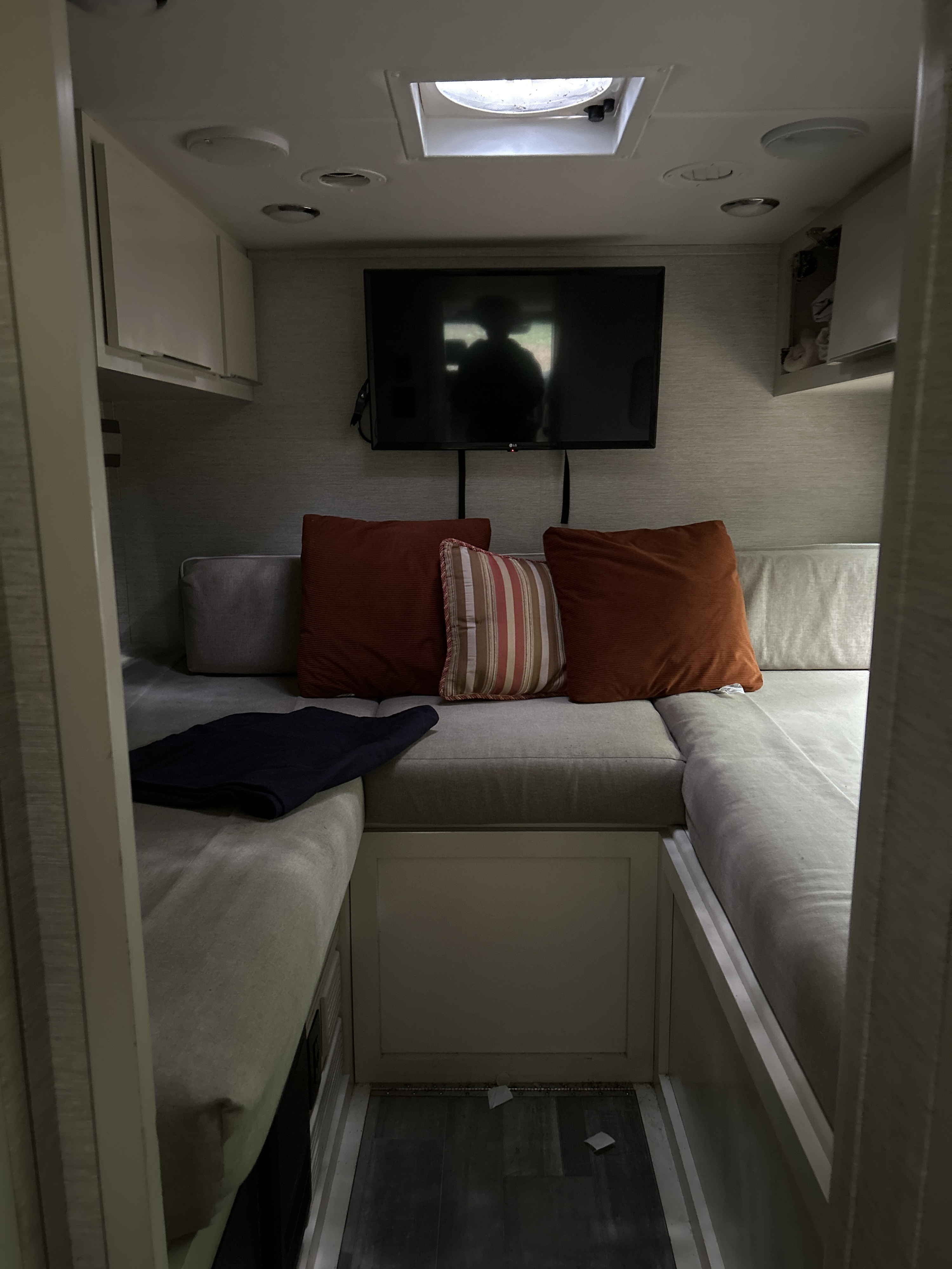 Cozy RV rental interior: lounge area with mounted TV, comfy cushions, overhead storage, and ceiling fan.. Wayfarer Wayfarer Motorhome 2020