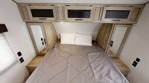A comfortable RV rental bedroom showing the queen bed, overhead cabinets, side mirrors & reading lights. Ideal for travel.. Forest River Cherokee Alpha Wolf 2020